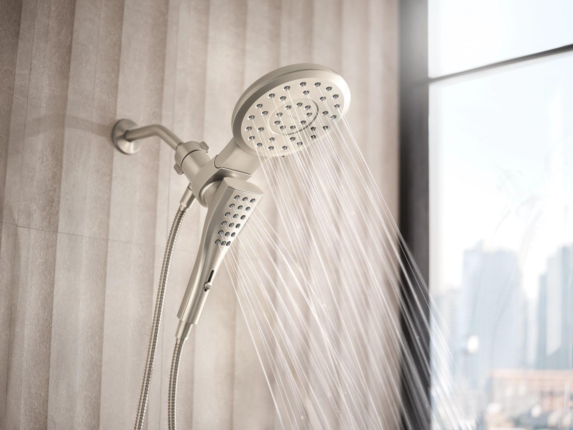 Brushed nickel round shower head with separate handheld spray and 72-inch hose mounted on bathroom wall.