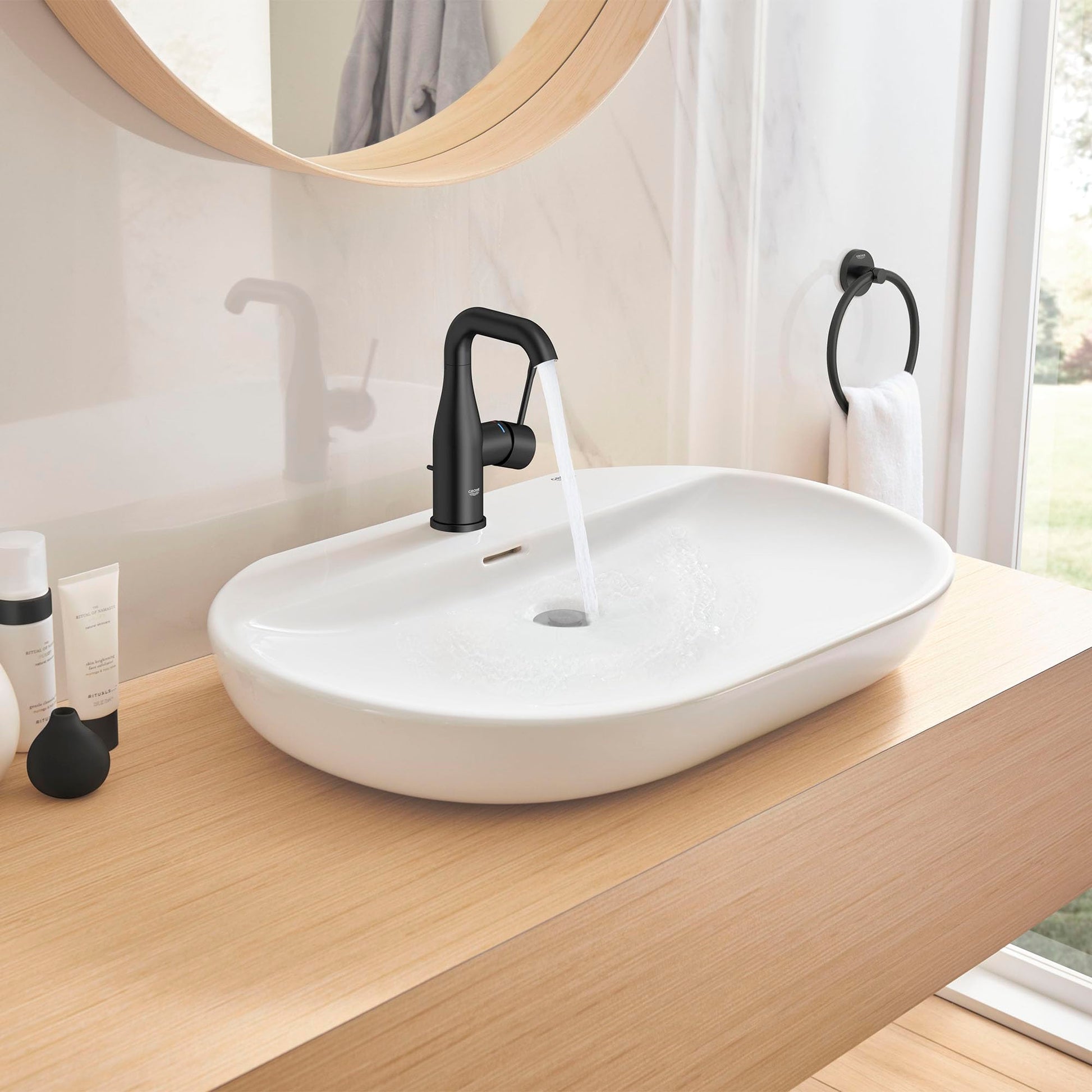 Matte black single-handle bathroom faucet with curved spout mounted on white oval sink.