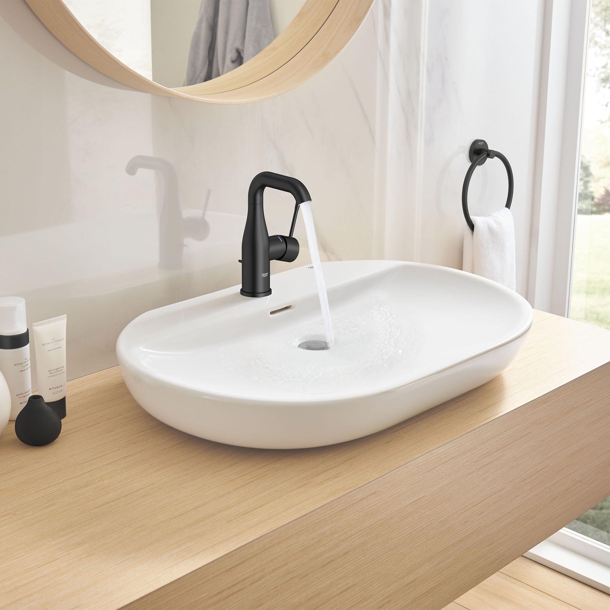 Matte black single-handle bathroom faucet with curved spout mounted on white oval sink.