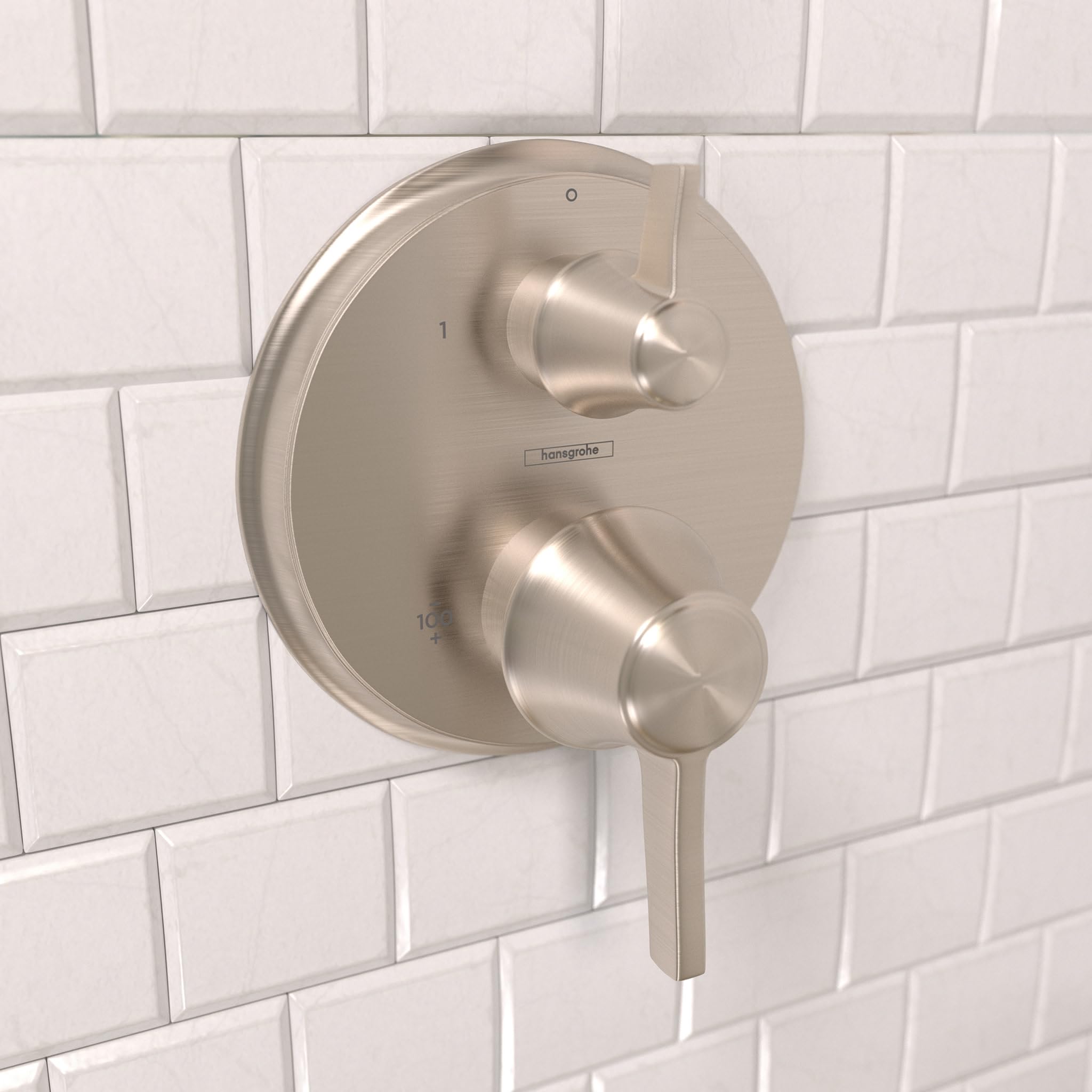 Round brushed nickel thermostatic shower trim with two control knobs mounted on white subway tile wall.