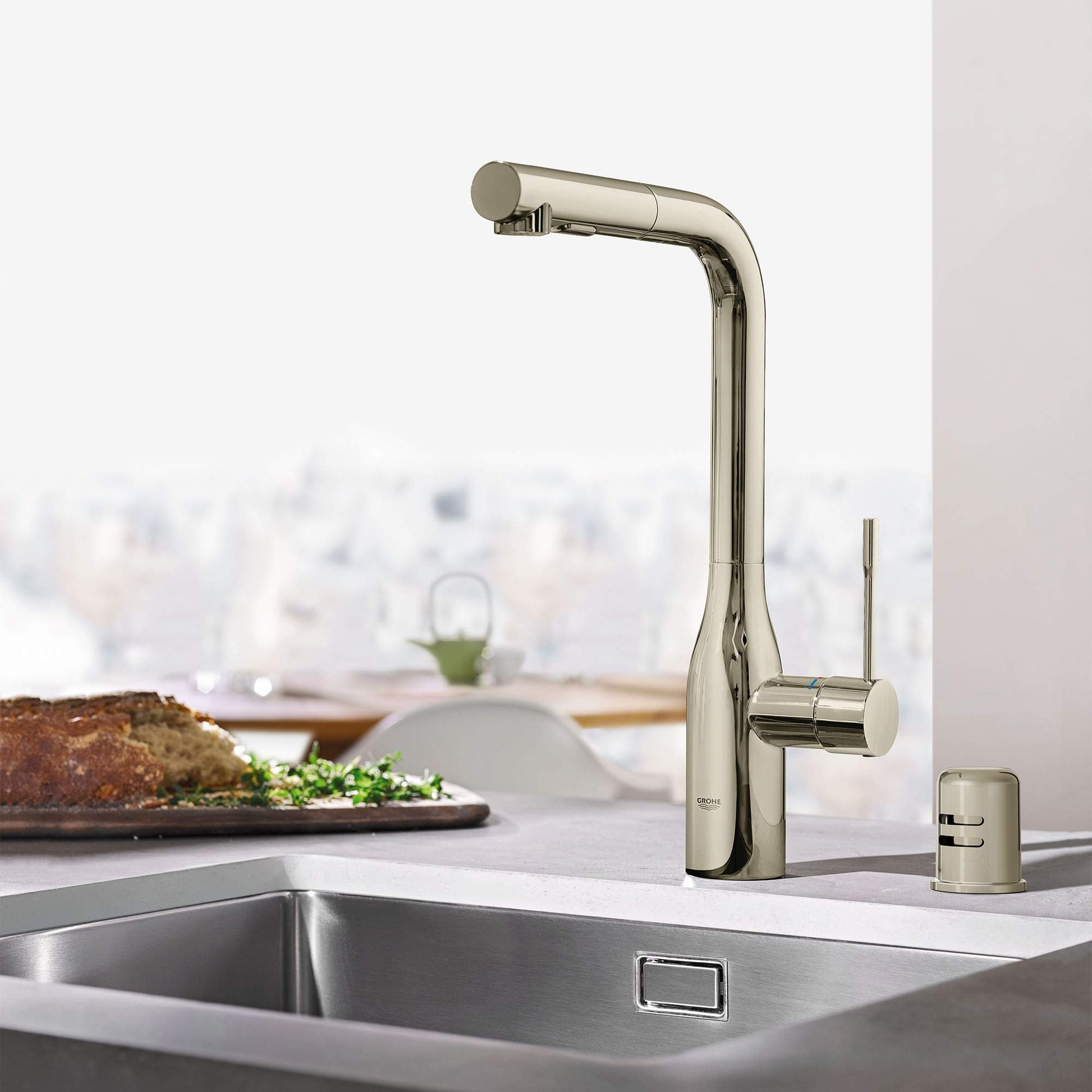 Polished nickel air gap component with cylindrical body and small cap, displayed next to kitchen sink faucet.