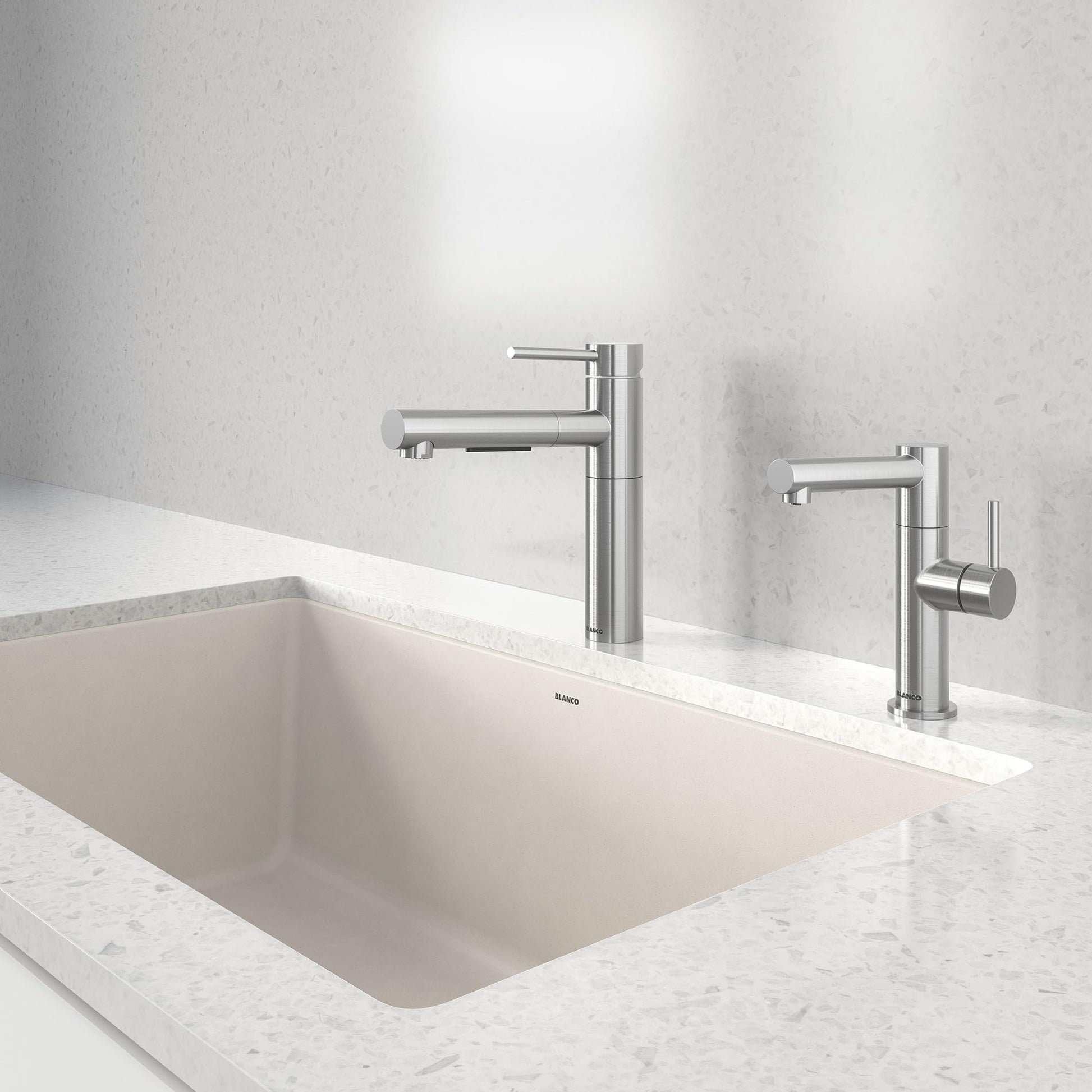 Stainless steel pull-out kitchen faucet with tall cylindrical spout mounted above white undermount sink on marble countertop.