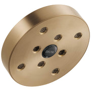 Round brushed gold showerhead with multiple spray holes and Delta logo in center.