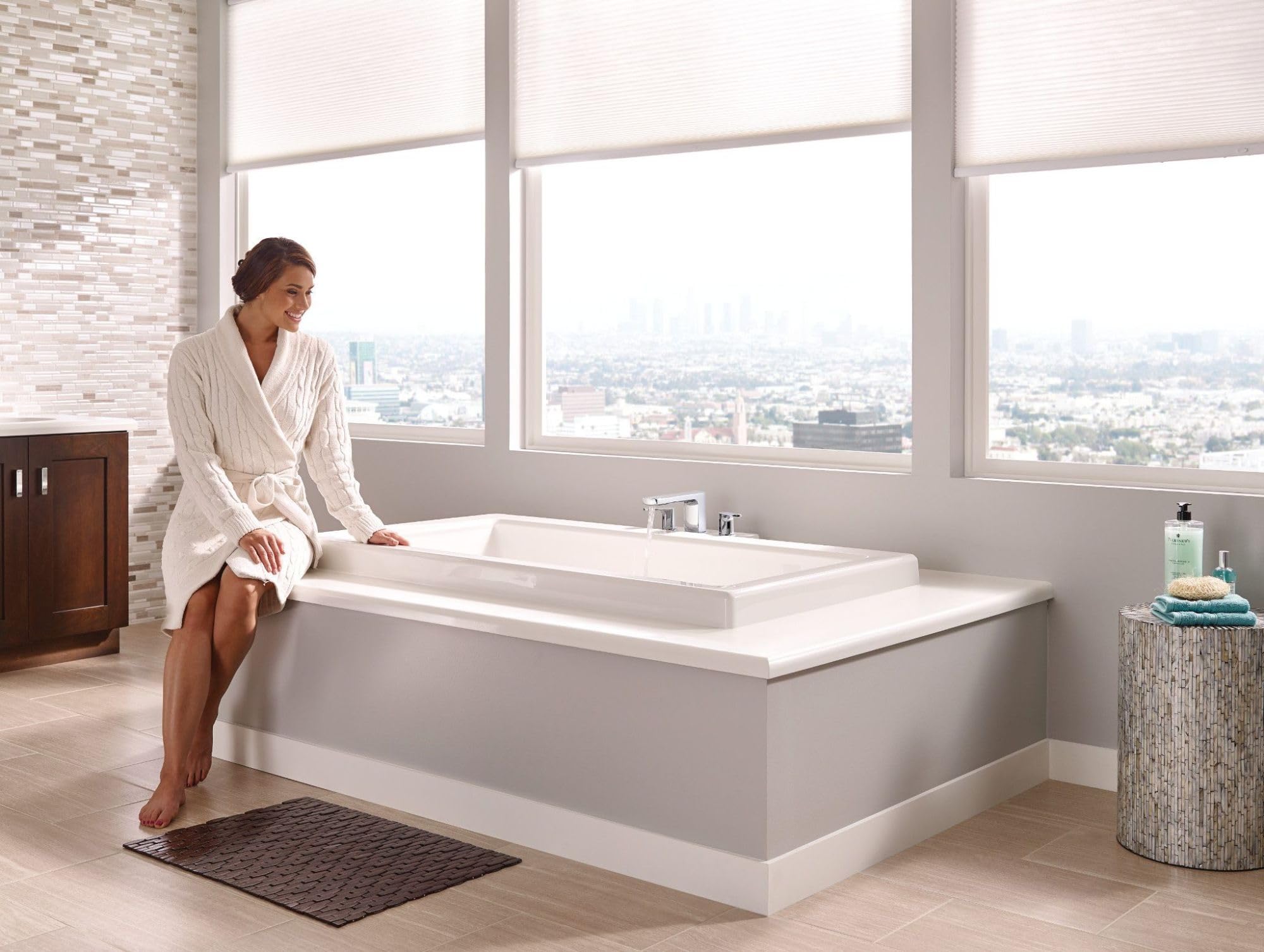 Chrome two-handle deck mount roman tub faucet trim with modern design installed on white bathtub.