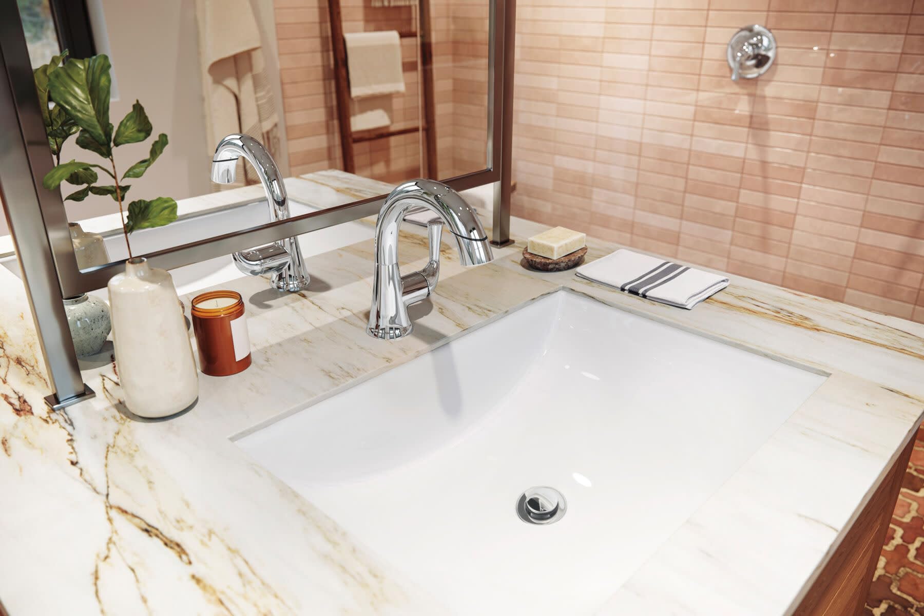 Polished chrome single-handle pull-down faucet installed above white rectangular bathroom sink with marble countertop.