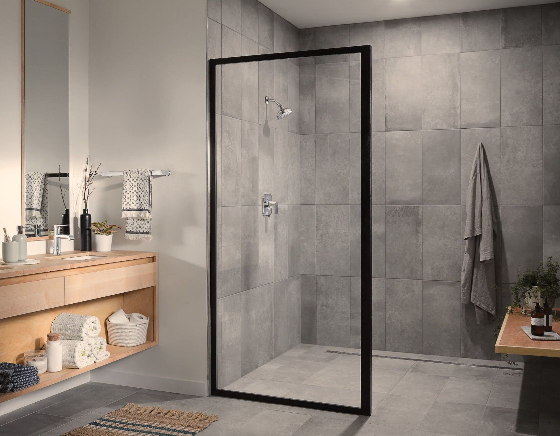 Chrome single-handle shower valve trim with lever handle mounted on gray tiled shower wall.