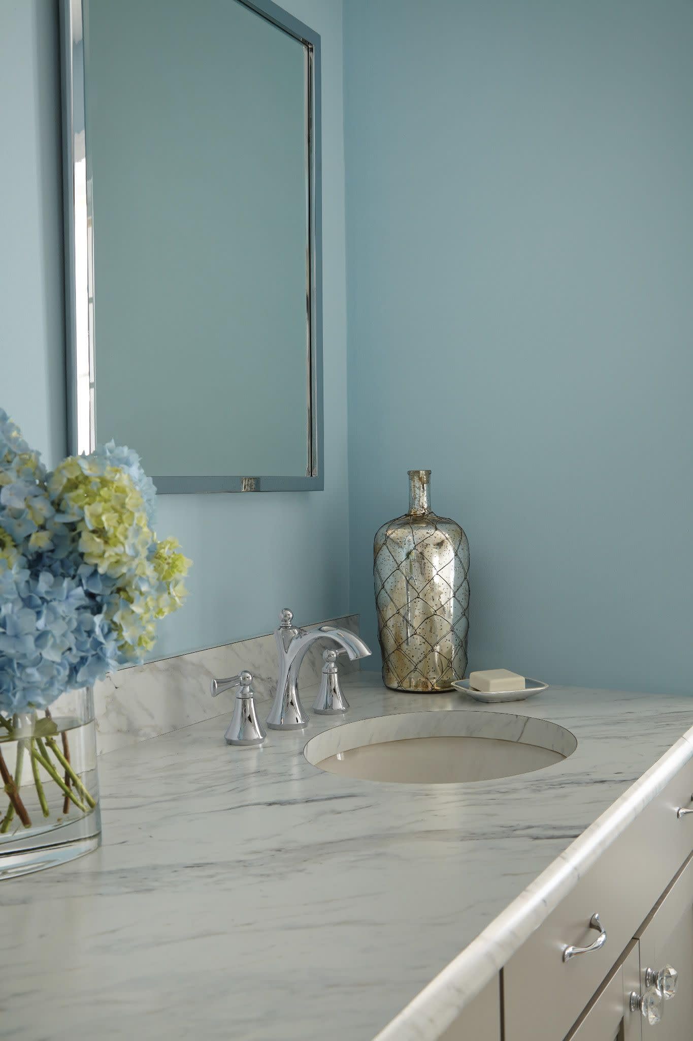 Chrome two-handle bathroom faucet with high arc spout and lever handles installed on marble vanity.