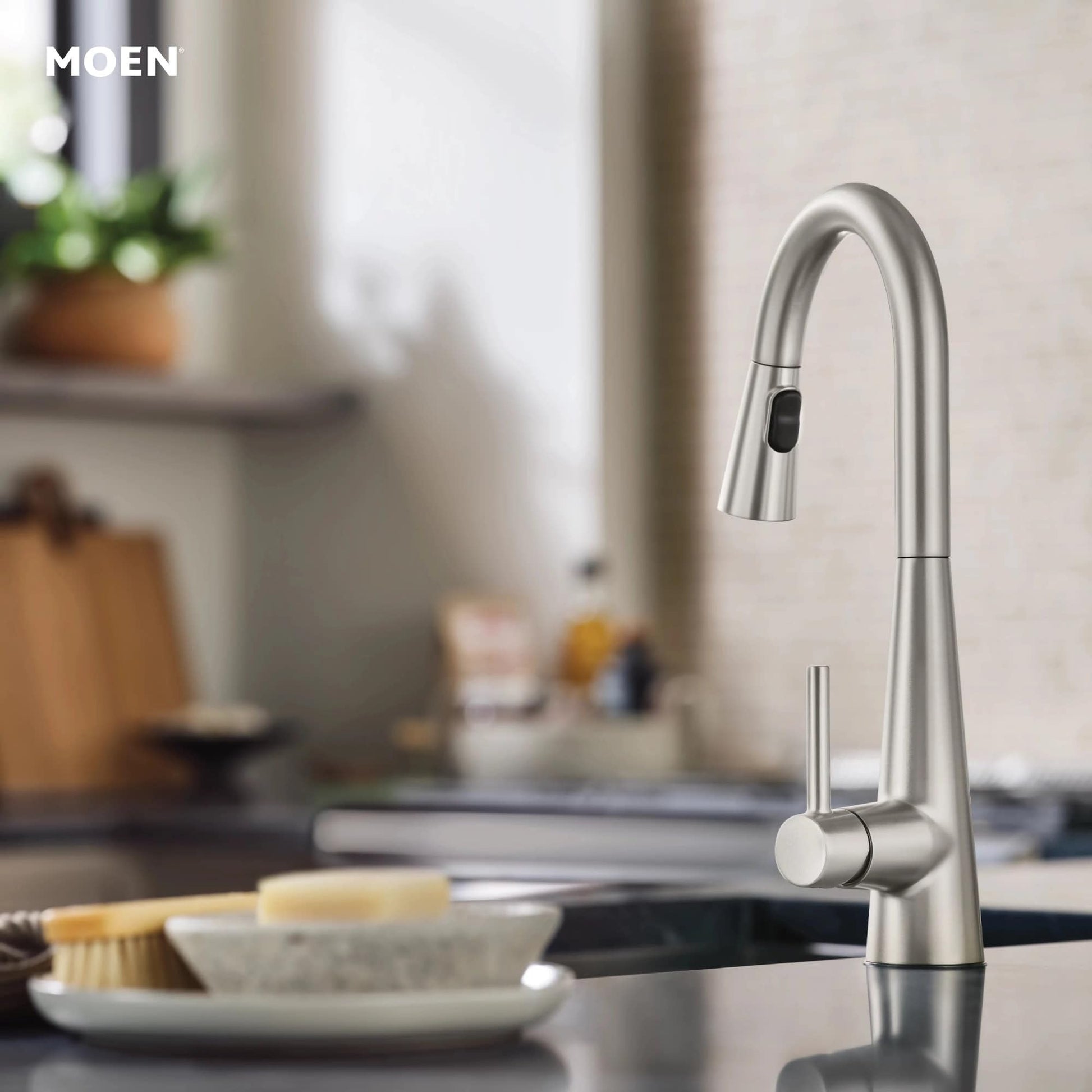 Stainless steel pull-down kitchen faucet with curved spout and touchless sensor mounted on sink deck.