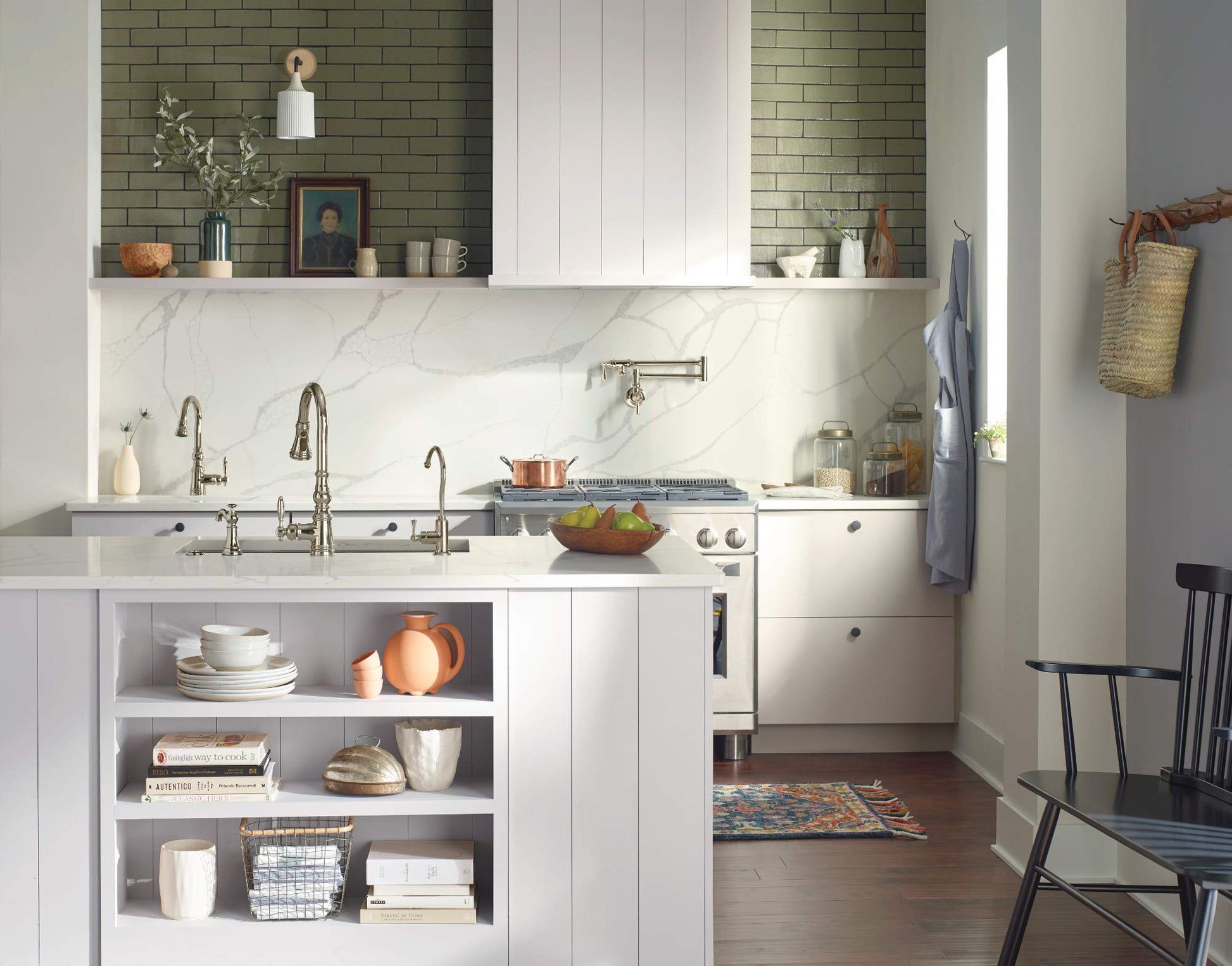 Chrome pulldown kitchen faucet with curved spout and metal wand mounted above white marble countertop sink.