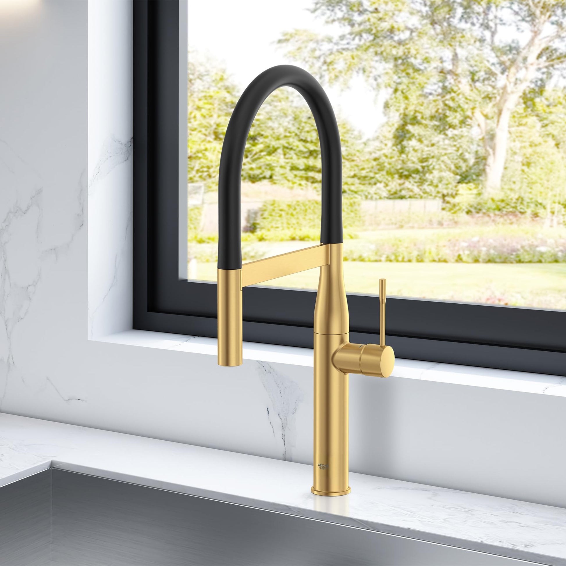 Brushed gold kitchen faucet with black pull-down spray head and single lever handle on white countertop.