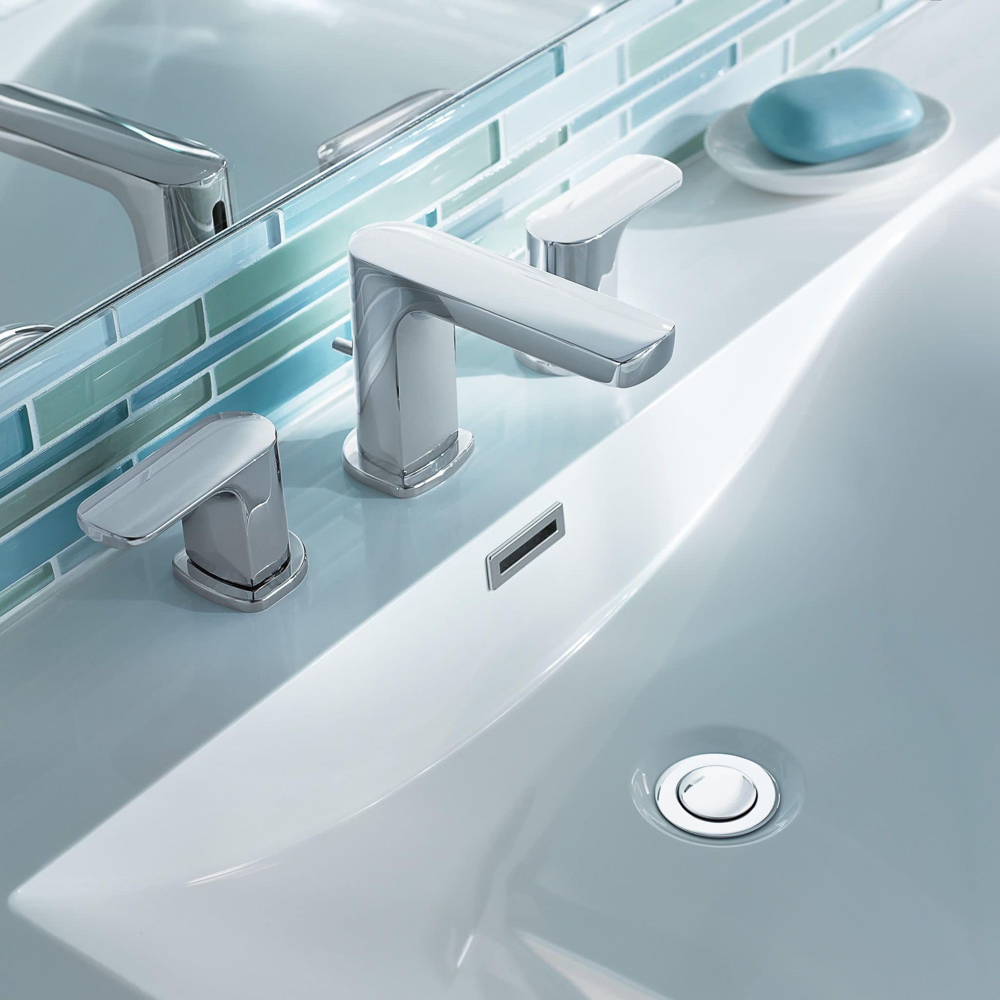 Chrome two-handle widespread bathroom faucet with rectangular spout installed on white sink counter.