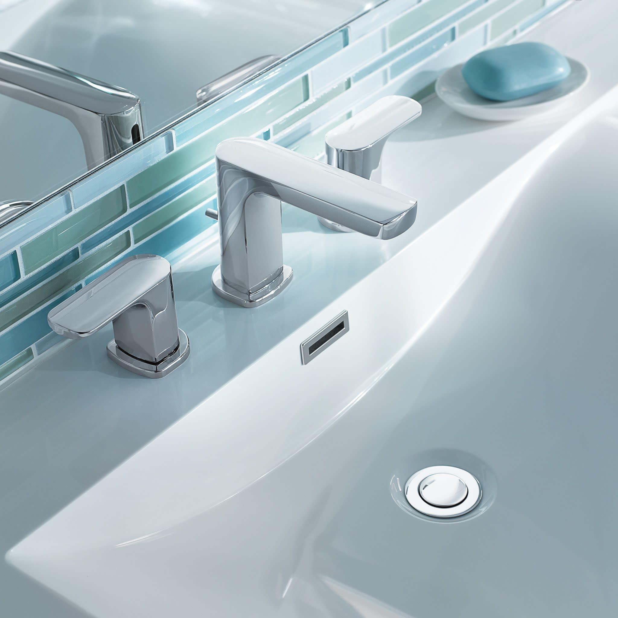 Chrome two-handle widespread bathroom faucet with rectangular spout installed on white sink counter.