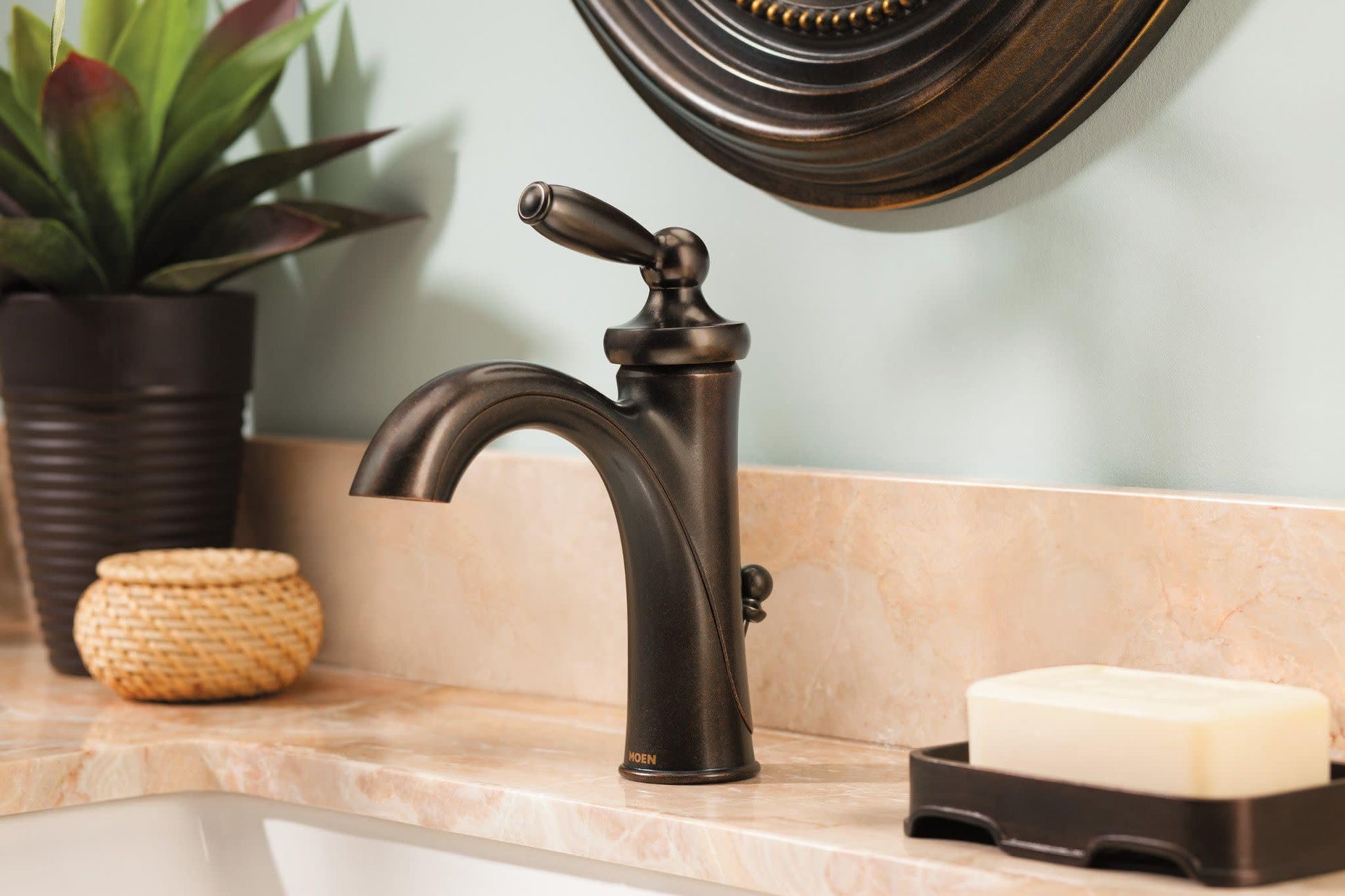 Oil rubbed bronze single-handle bathroom faucet with curved spout and lever handle on marble countertop.