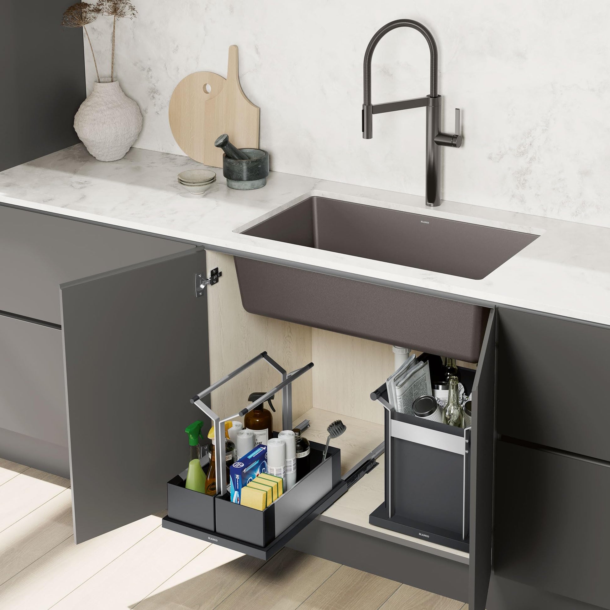 Black double-compartment storage caddy with handles installed under kitchen sink, containing cleaning supplies and bottles.