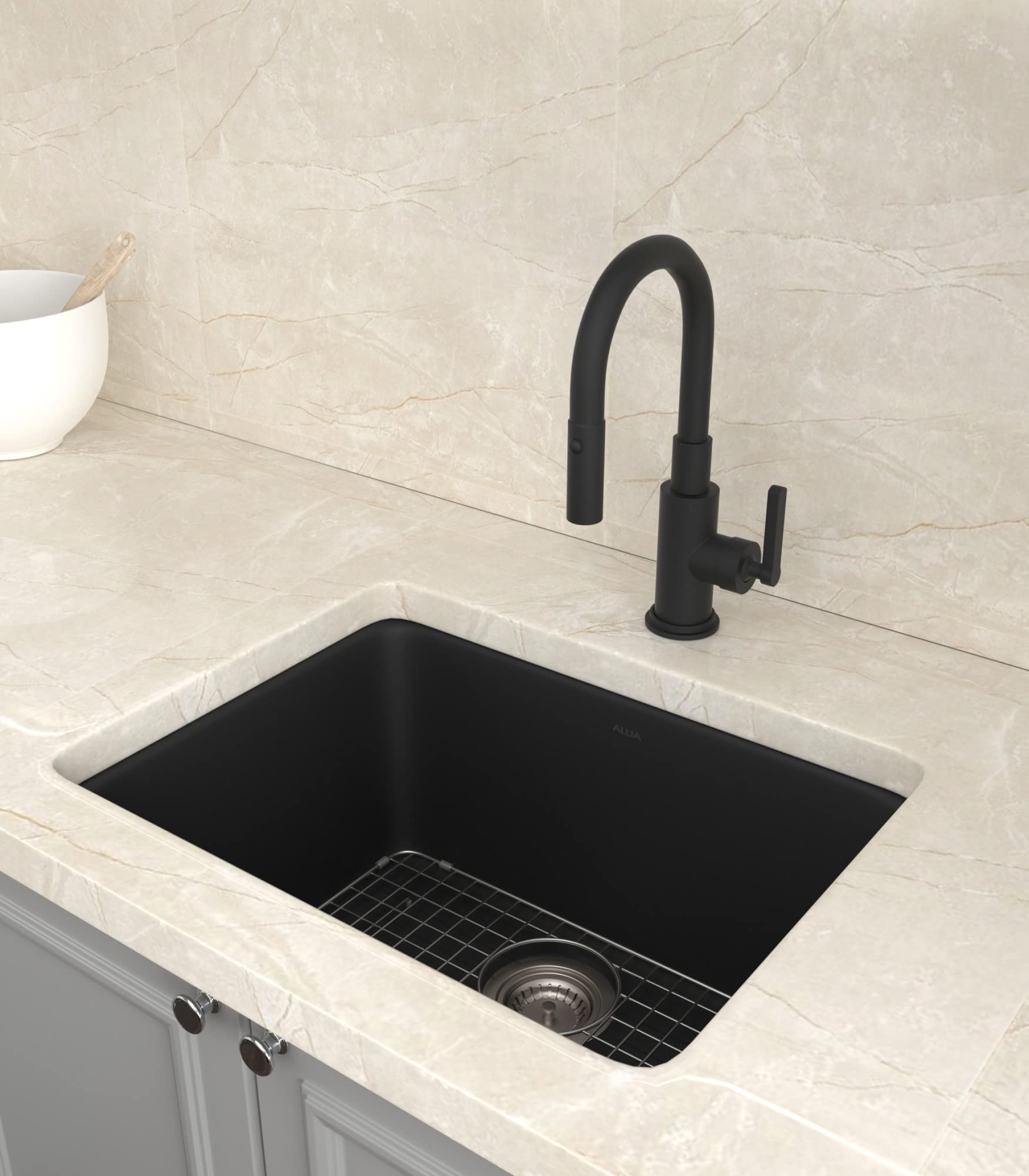 Black fireclay undermount sink with white rim installed in light marble countertop, paired with black pull-down faucet.