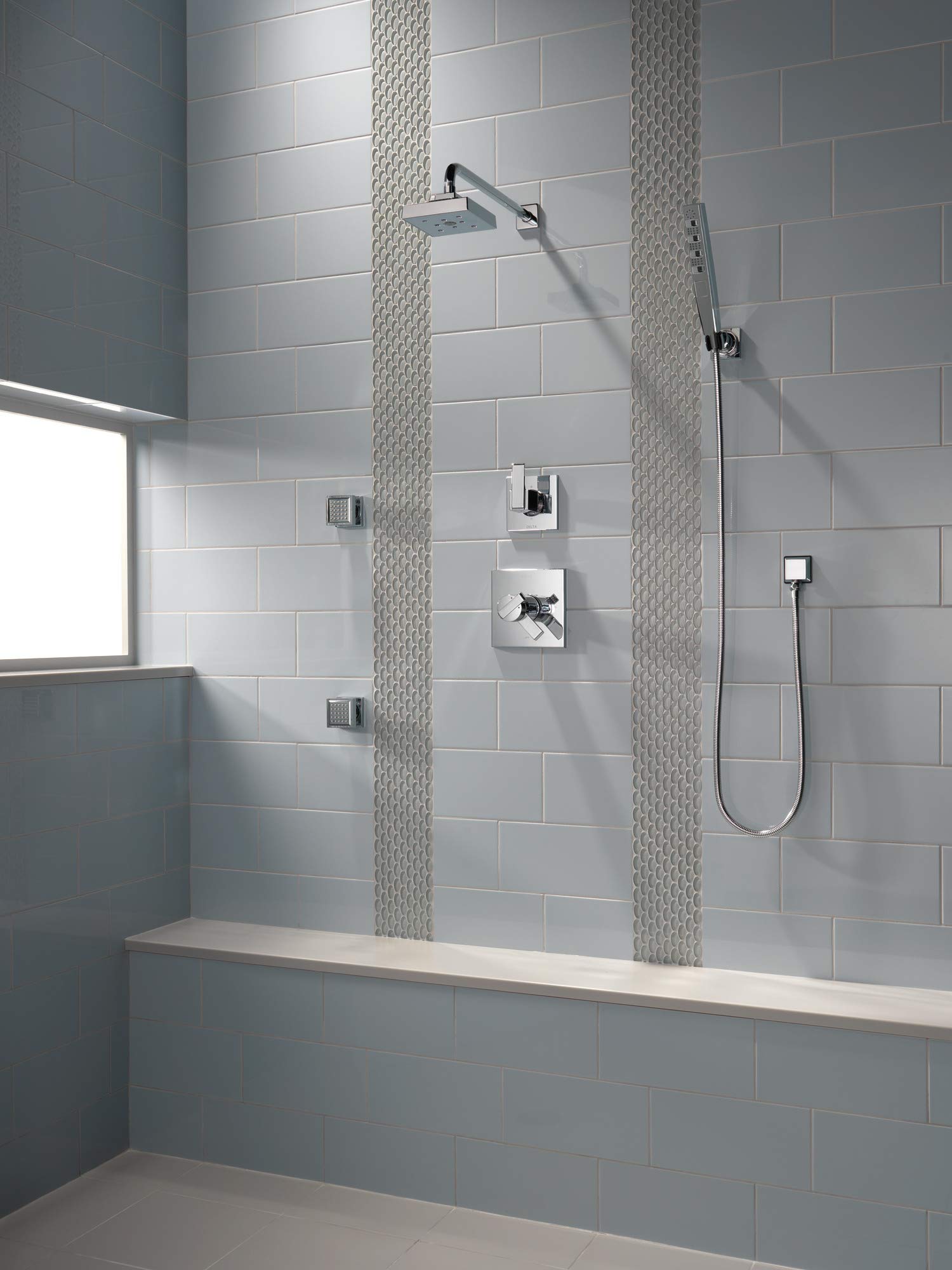 Black stainless steel shower arm mounted horizontally on tiled bathroom wall with water spray visible.