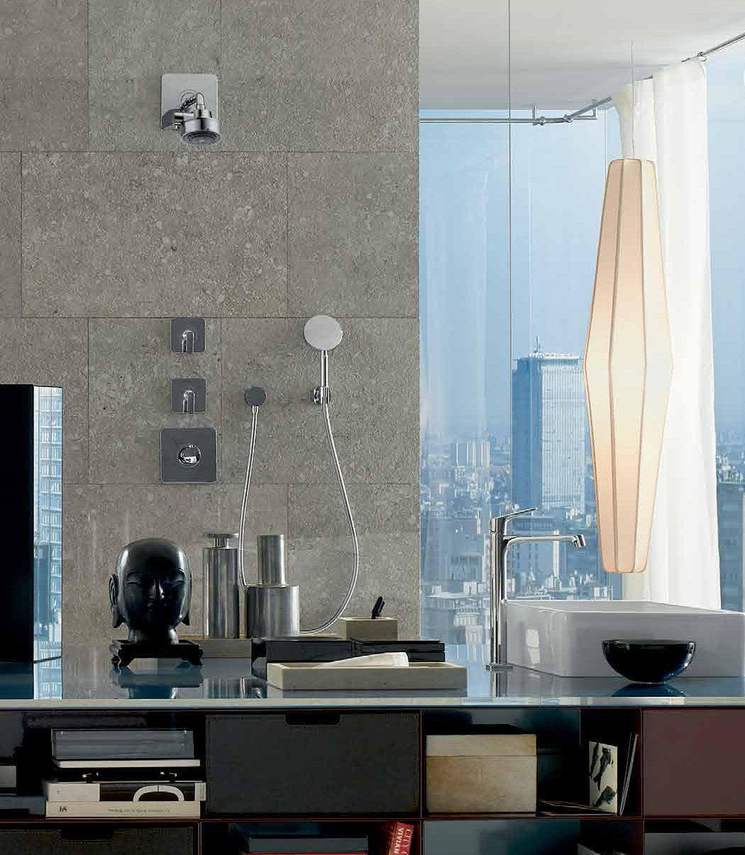 Chrome thermostatic shower trim with round trim plate and matching showerhead mounted on gray tile wall.