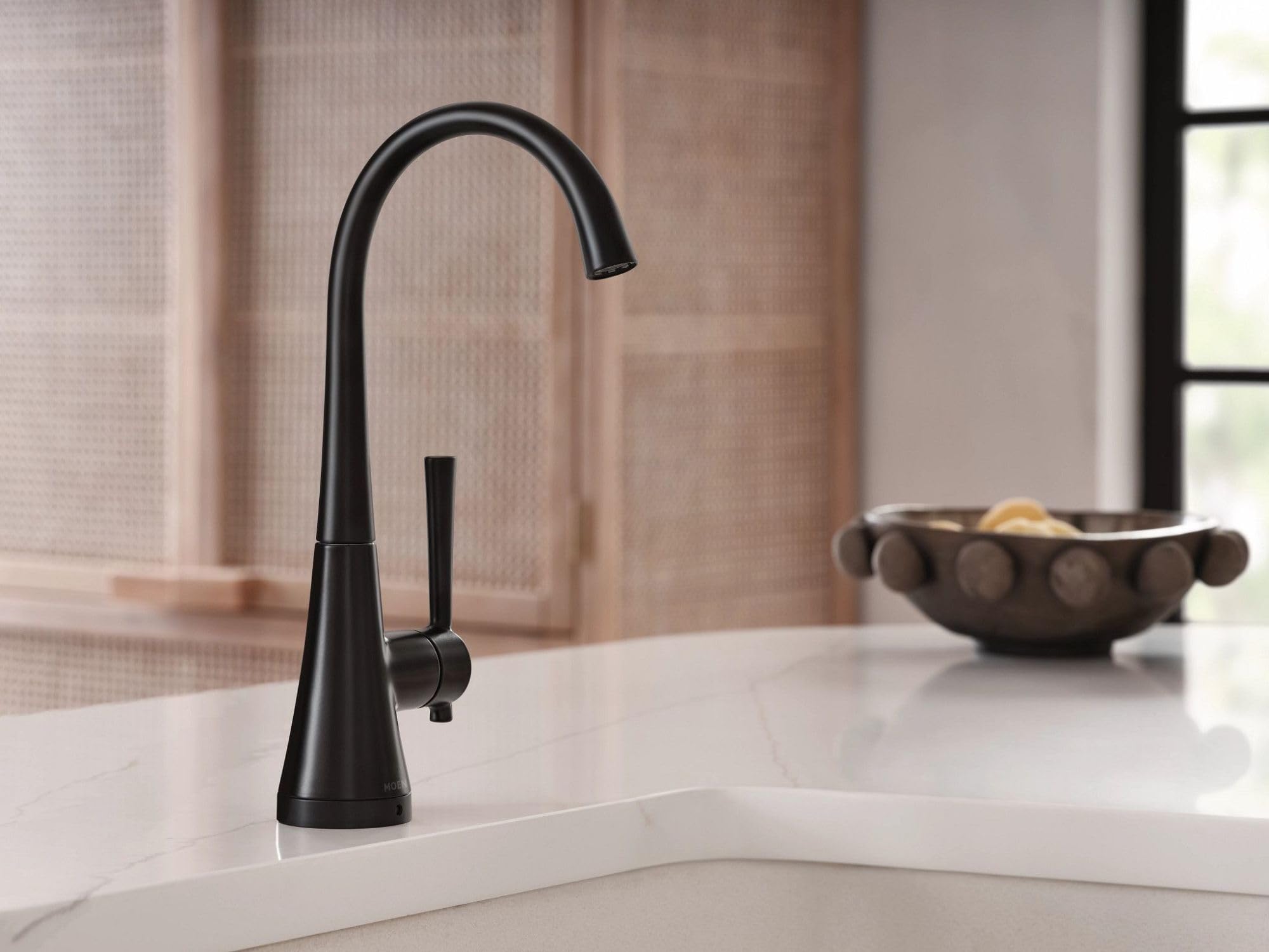 Matte black single-handle high-arc beverage faucet with curved spout mounted on white countertop.