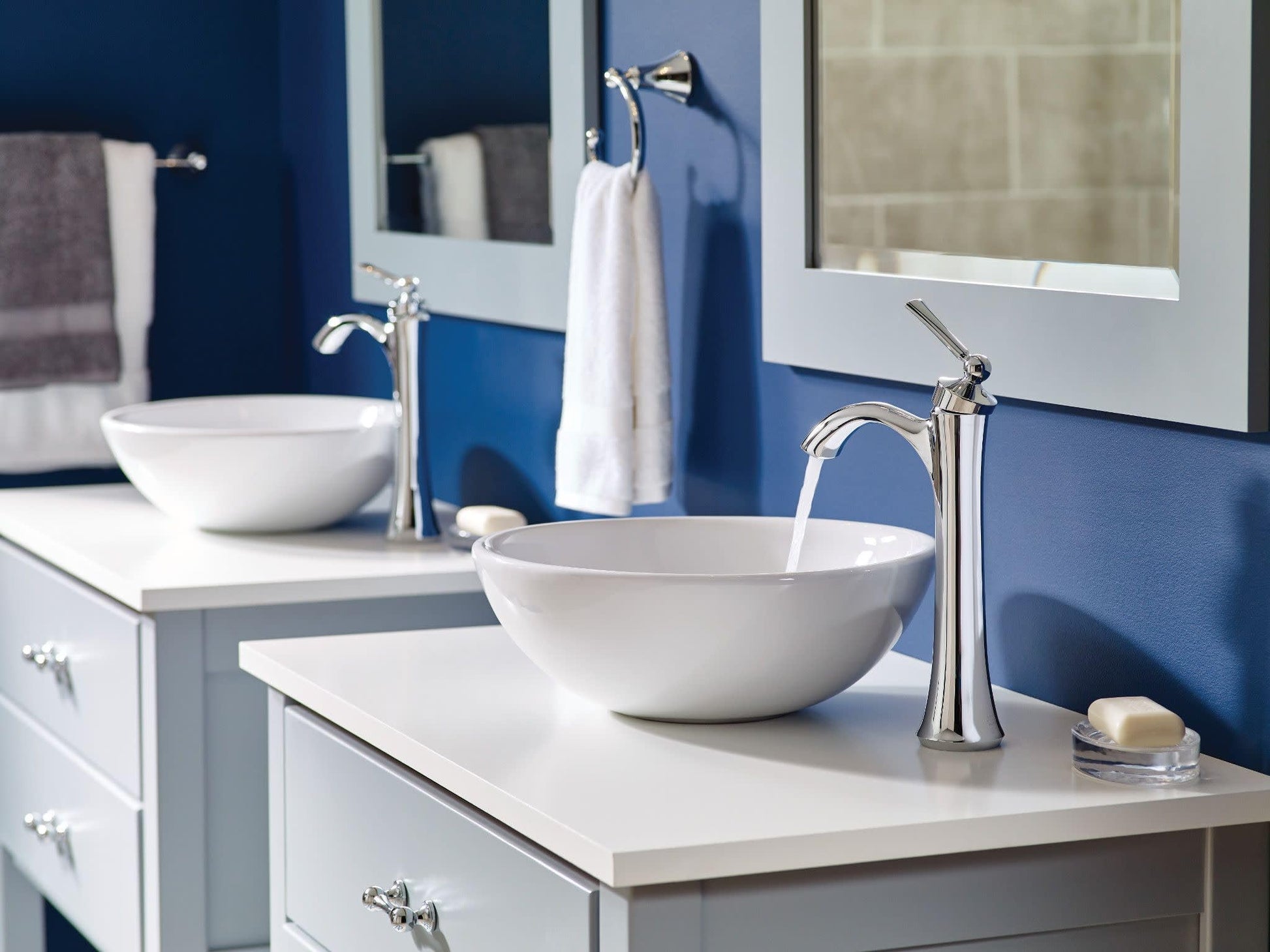 Brushed nickel single-handle high-arc faucet with curved spout mounted above white vessel sink on bathroom vanity.