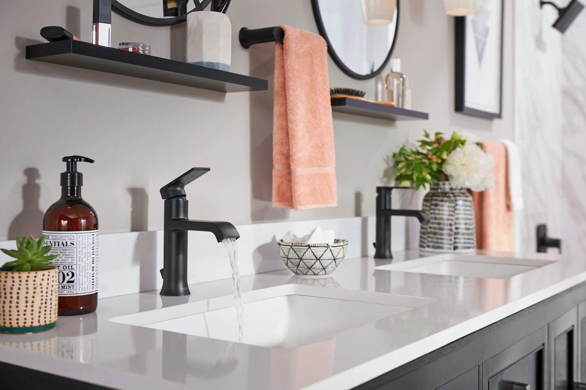 Black metal hand towel bar mounted on white bathroom wall holding folded coral towels.