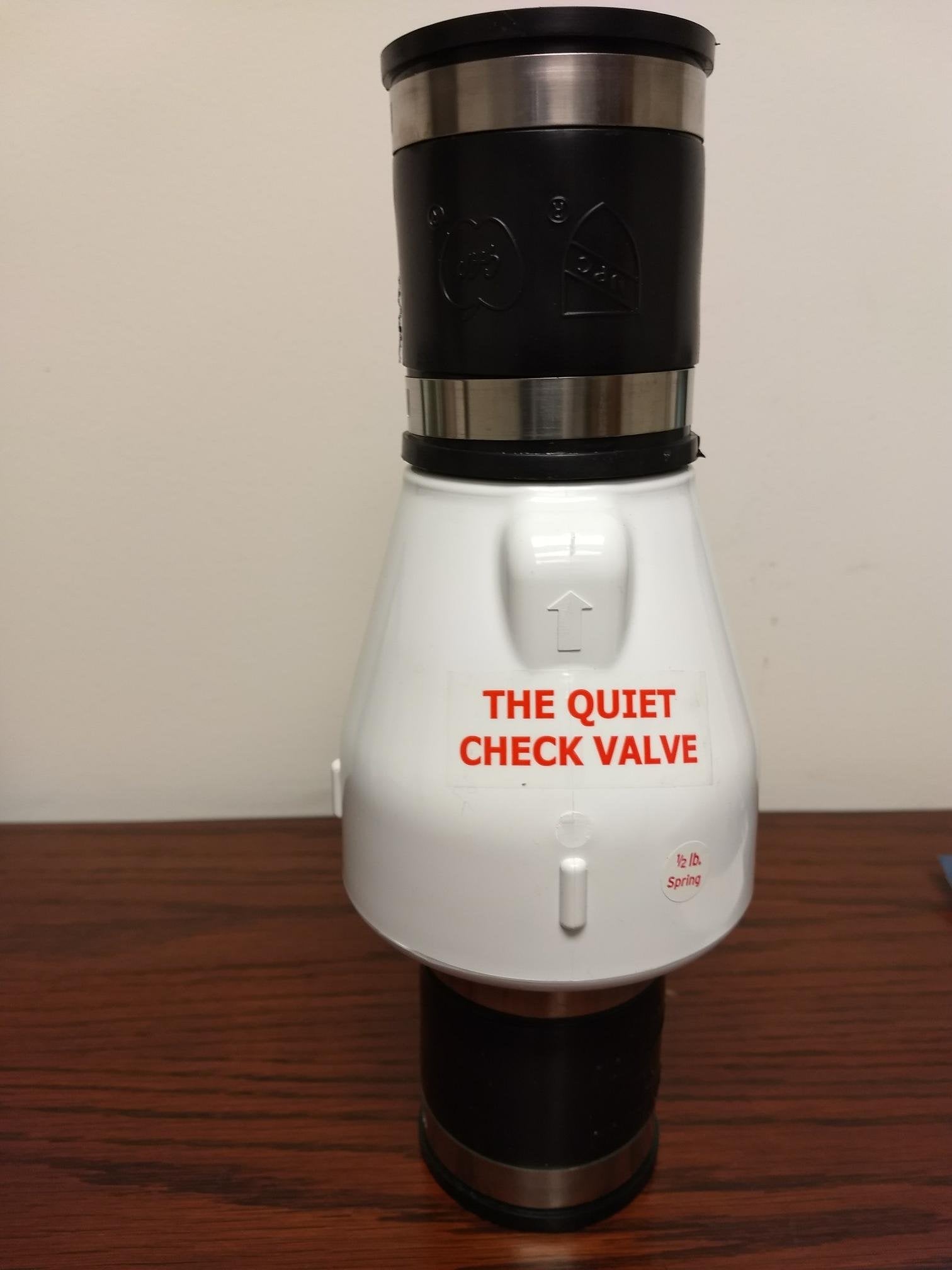 Two-inch PVC check valve with black top and bottom sections, white middle body labeled "The Quiet Check Valve," and metal ban