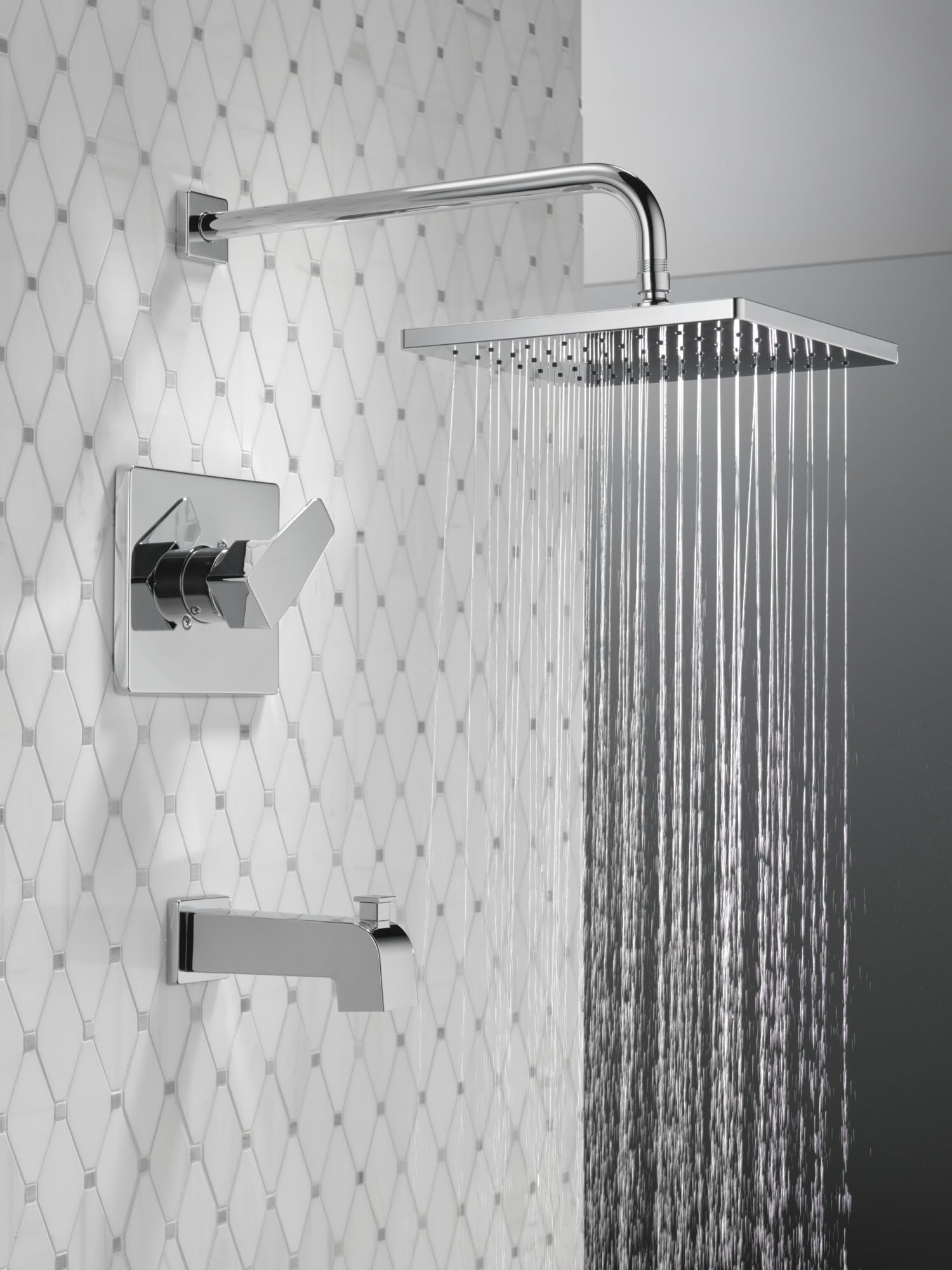 Chrome tub and shower trim with square showerhead, curved arm, valve control, and tub spout mounted on tiled wall.