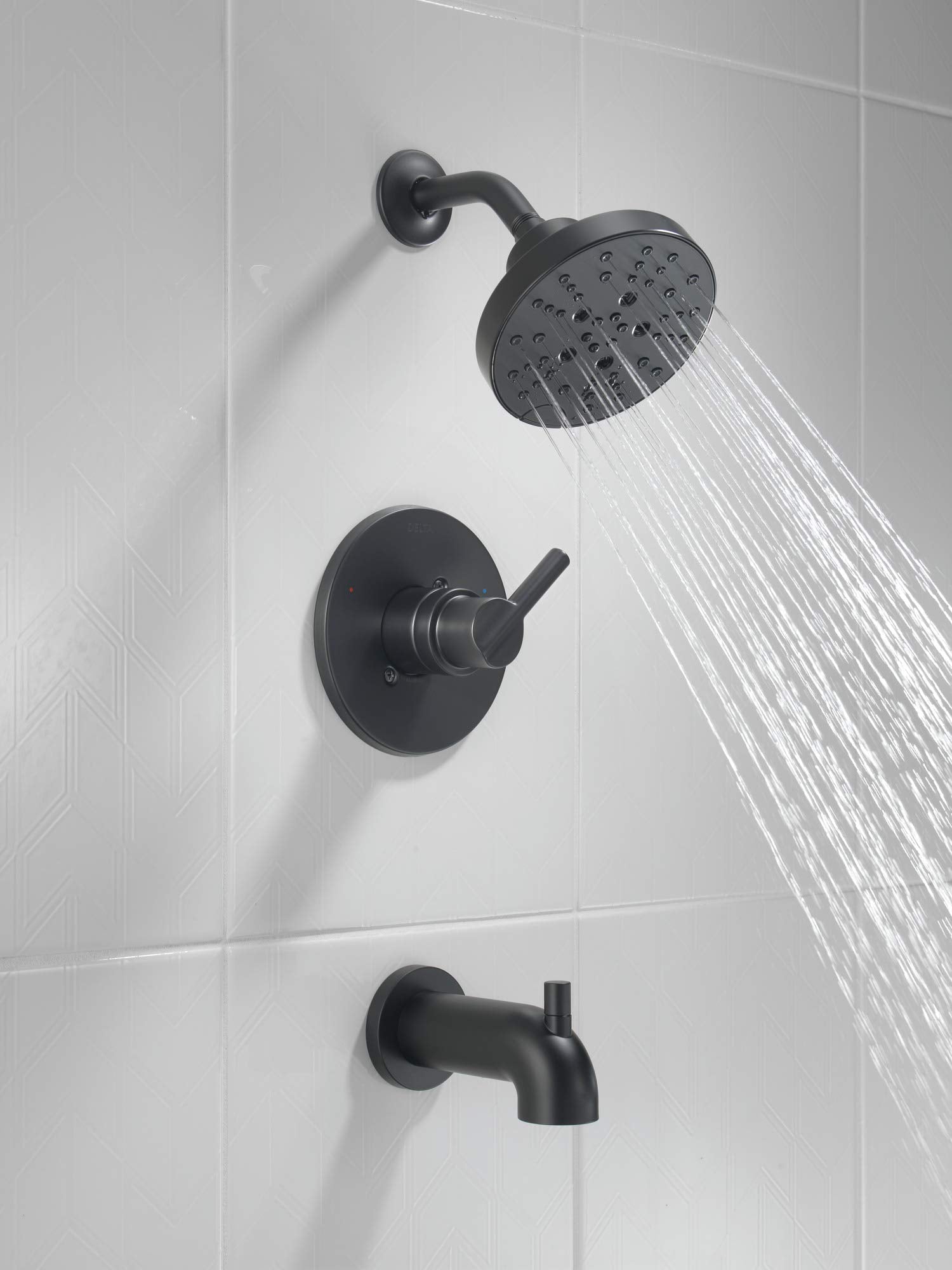 Matte black tub and shower system with round showerhead, control valve, and tub spout mounted on white tile wall.