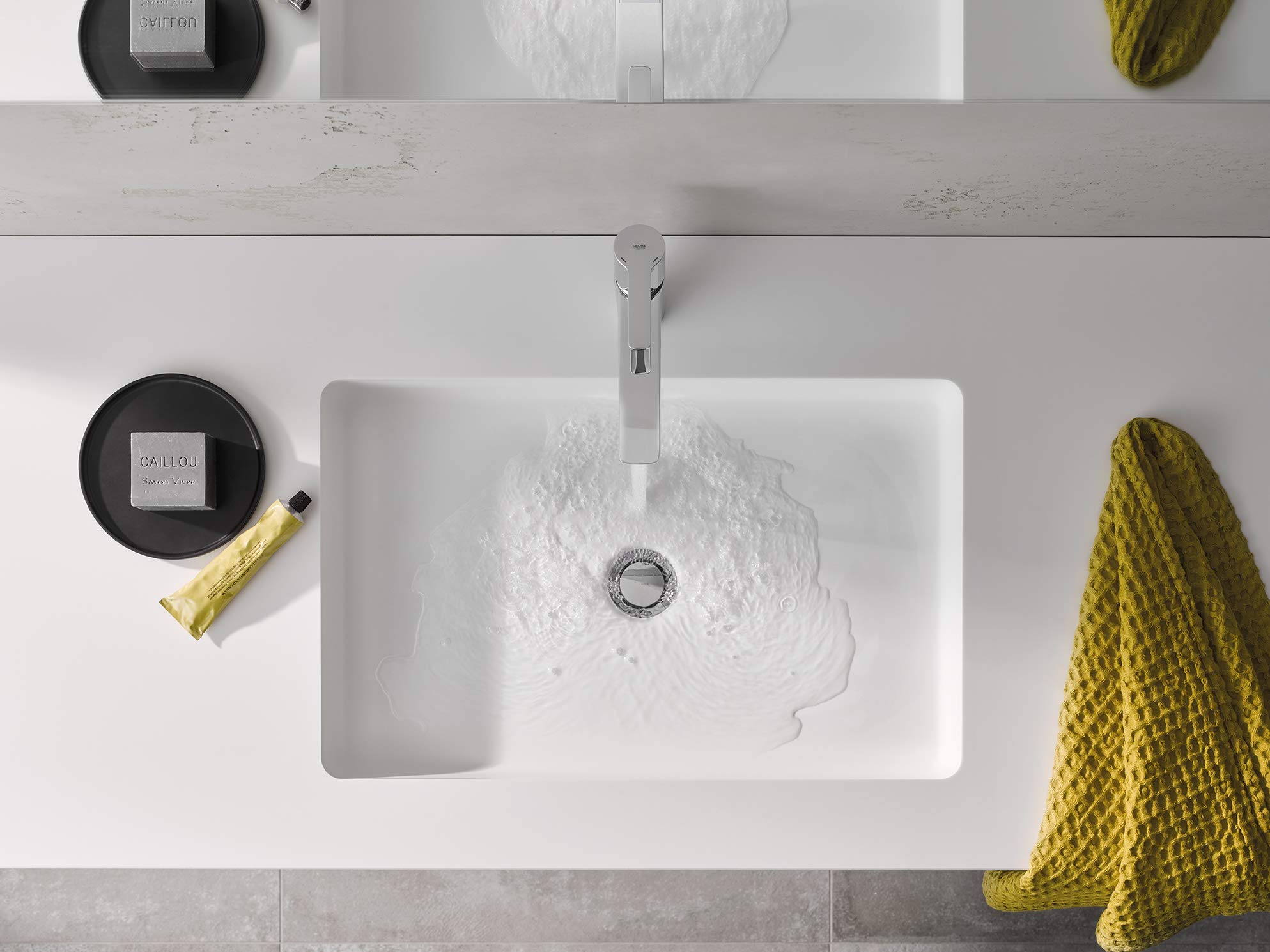 Chrome single-handle bathroom faucet with tall spout mounted on white rectangular sink basin.