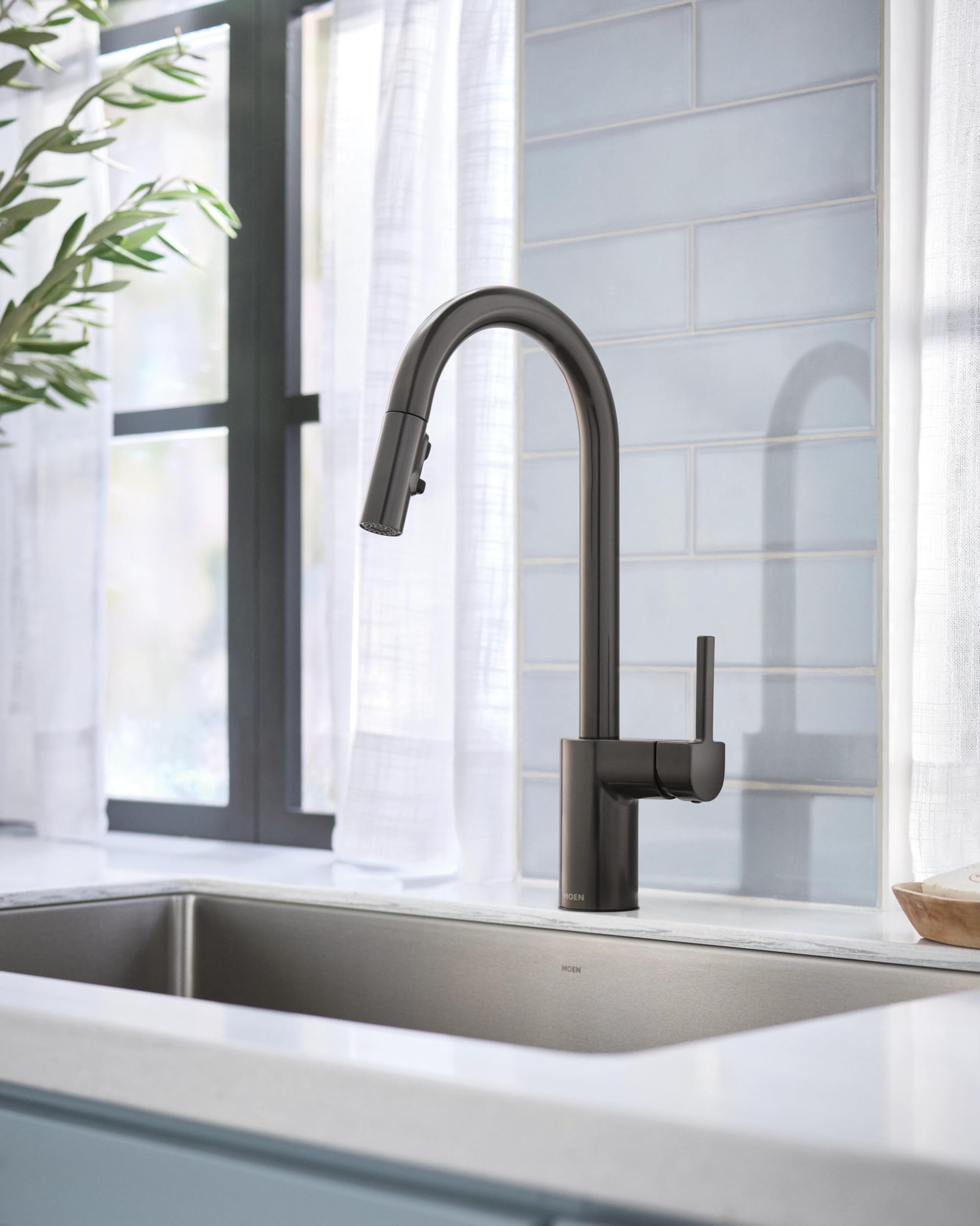 Black stainless steel kitchen faucet with pulldown spray head mounted above rectangular sink.