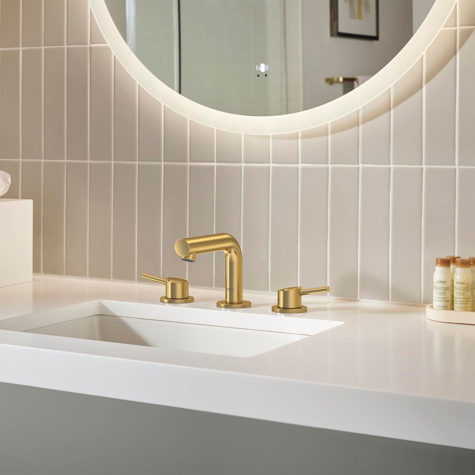 Brushed gold widespread bathroom faucet with two handles and curved spout installed on white sink countertop.