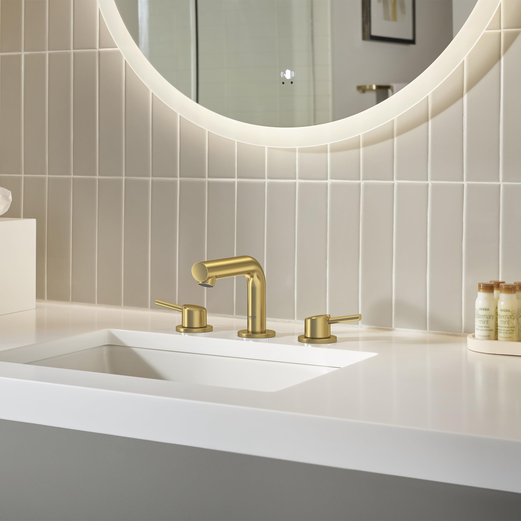 Brushed gold widespread bathroom faucet with two handles and curved spout installed on white sink countertop.