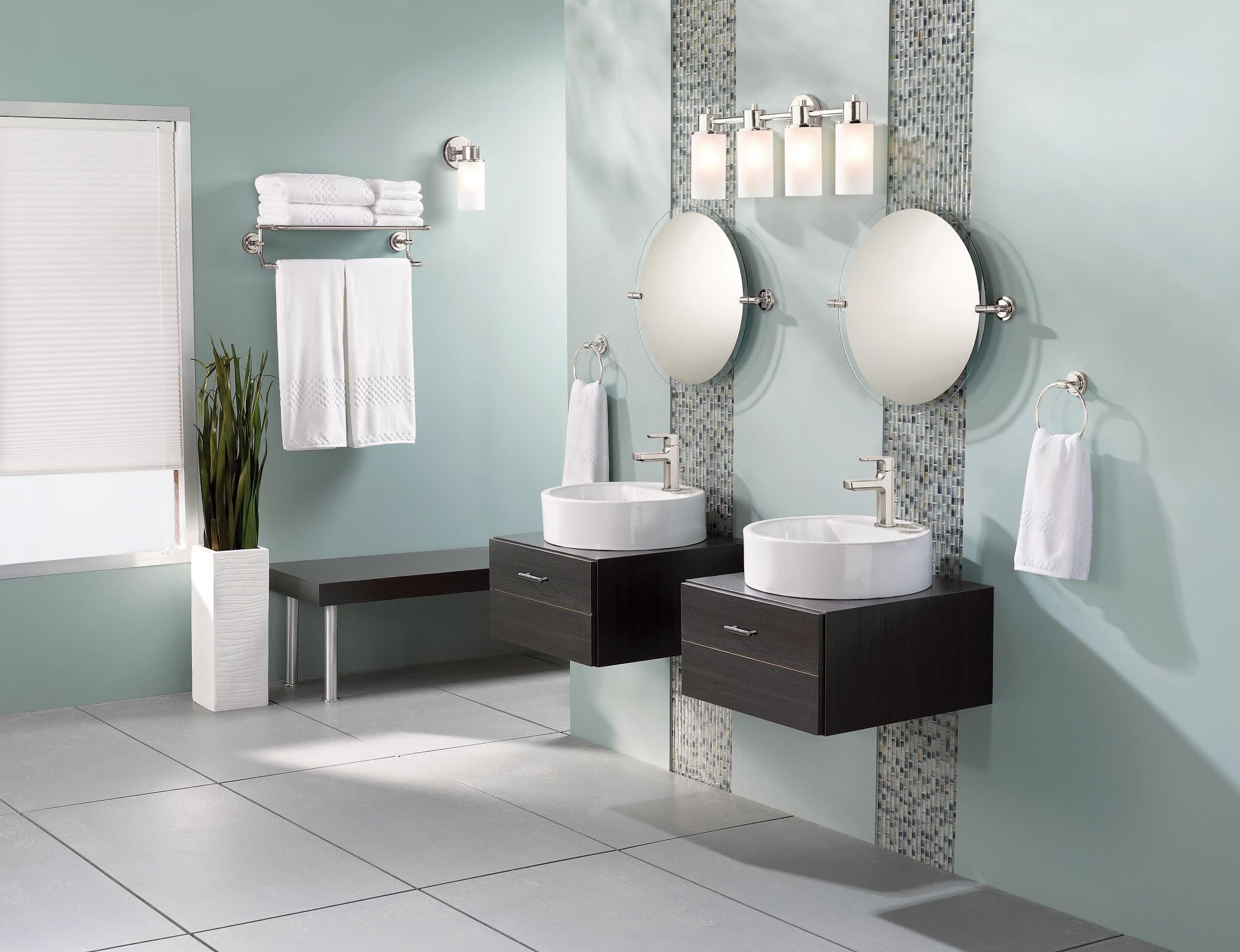 Chrome single-handle bathroom faucet with modern spout mounted on white vessel sink in styled bathroom setting.