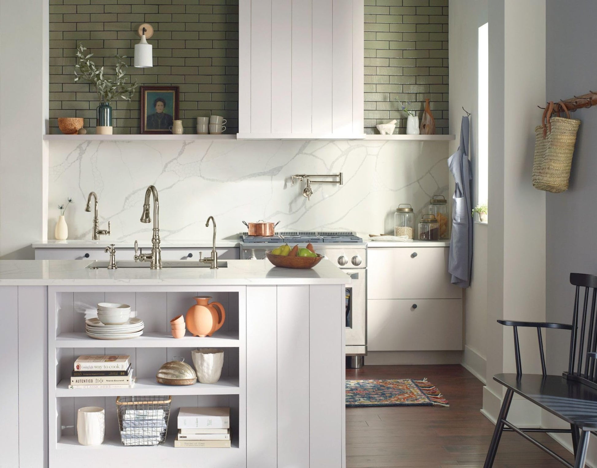Polished nickel wall-mounted swing arm pot filler faucet installed above kitchen sink with marble backsplash.