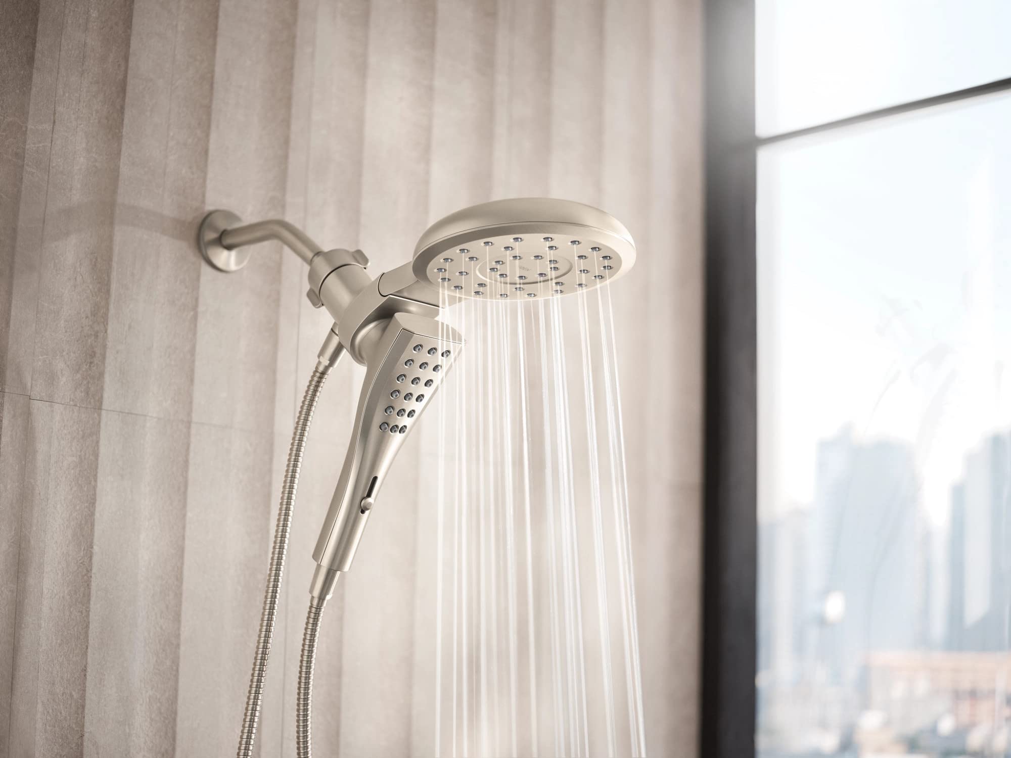 Brushed nickel round shower head with separate handheld sprayer connected by hose, mounted on wall arm.