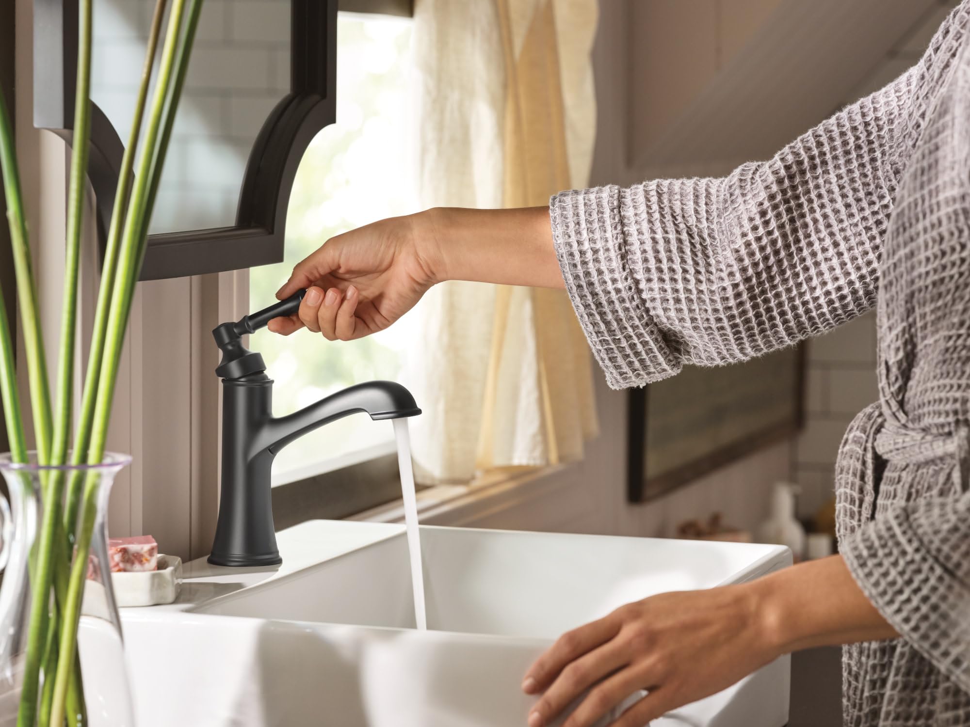 Matte black single-handle bathroom faucet with curved spout installed on white sink basin.