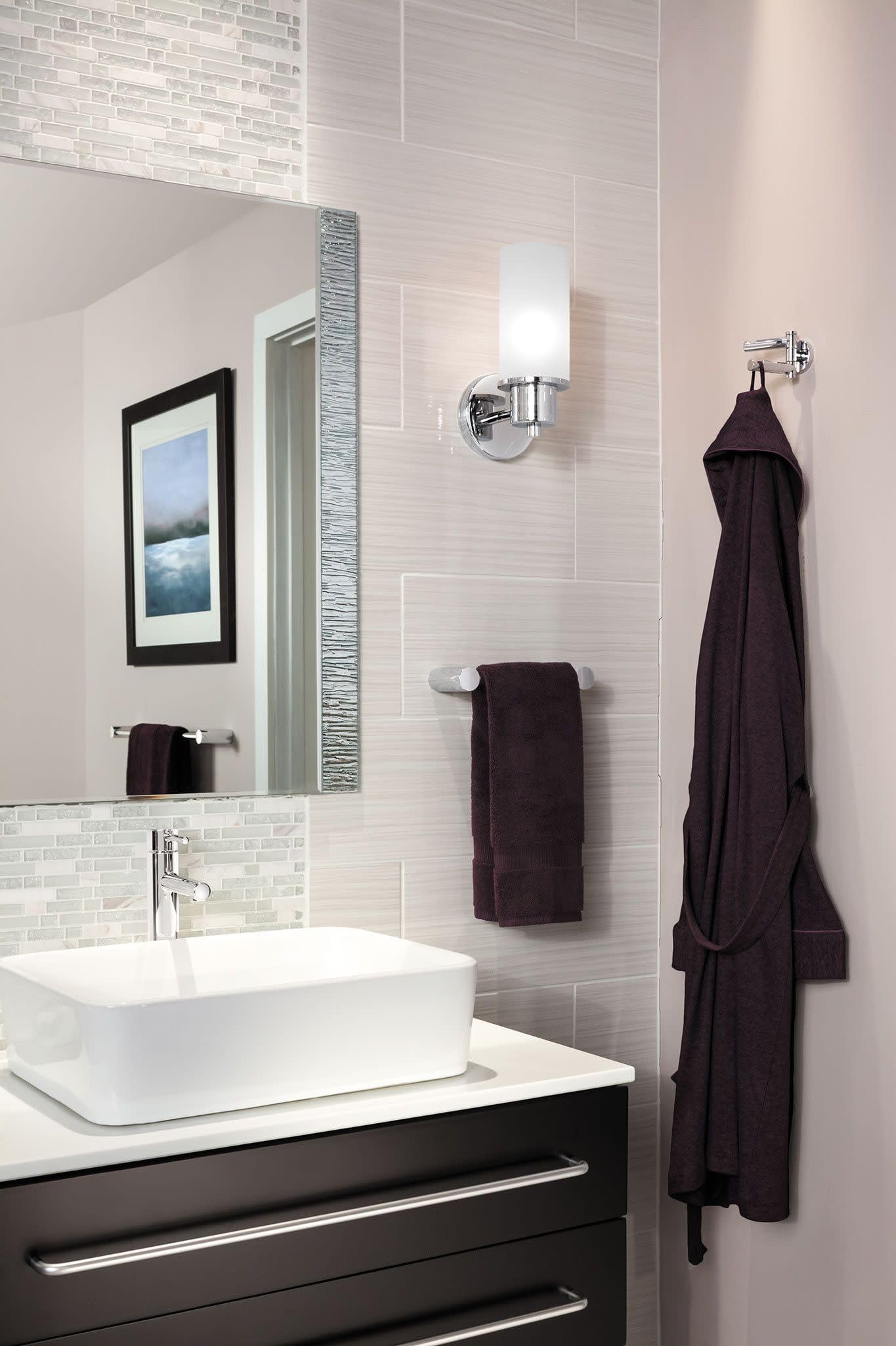 Chrome single-handle faucet with cylindrical spout mounted on white vessel sink in modern bathroom.