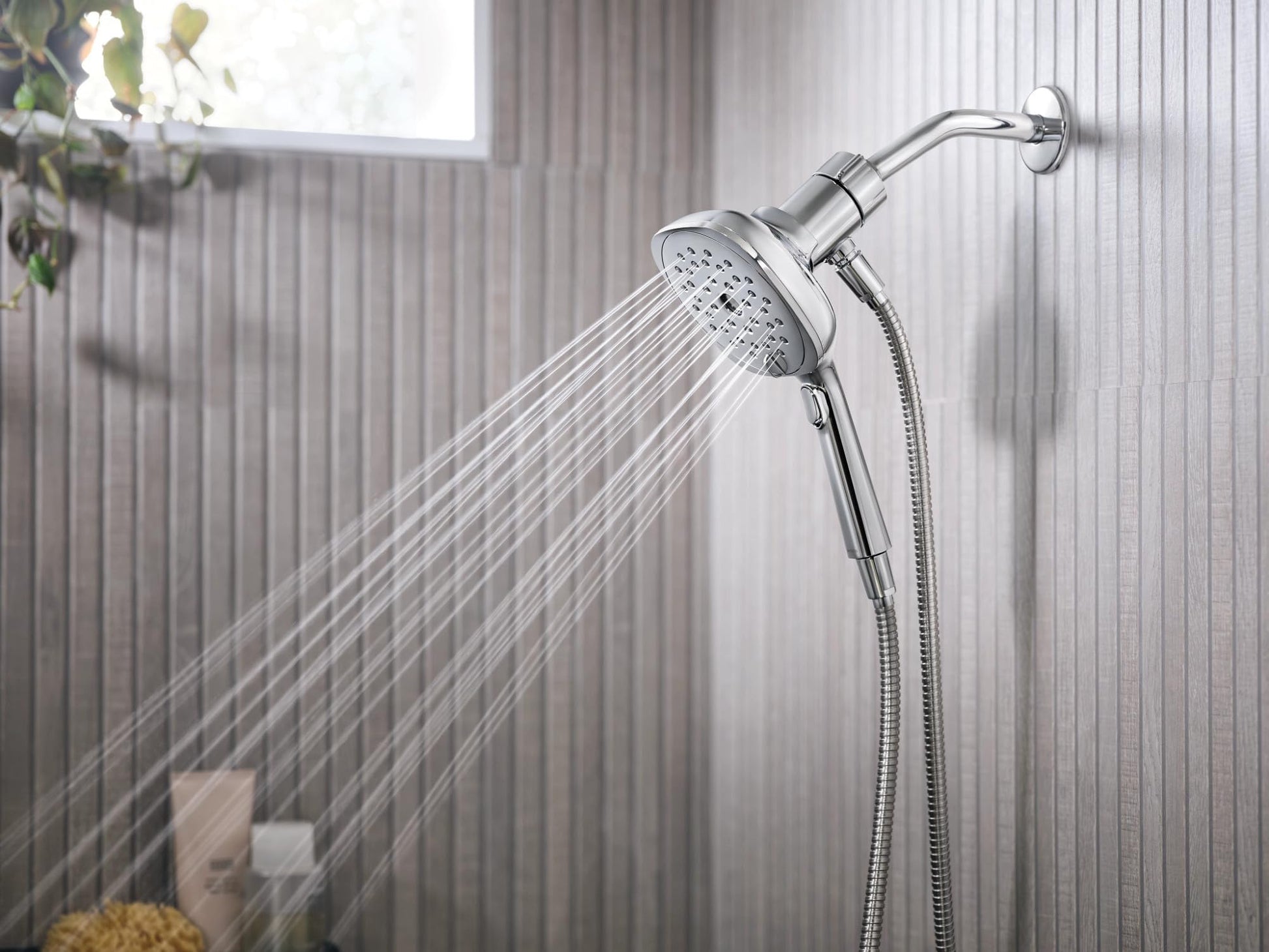 Chrome showerhead with 5-inch square face and dial controls mounted on wall with flexible hose connection.