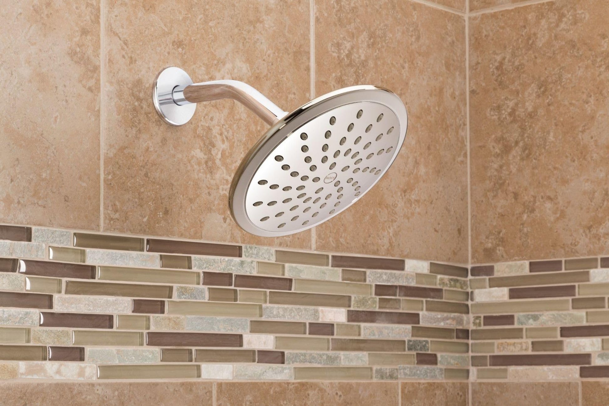 Chrome round rain shower head with curved arm mounted on tile bathroom wall.
