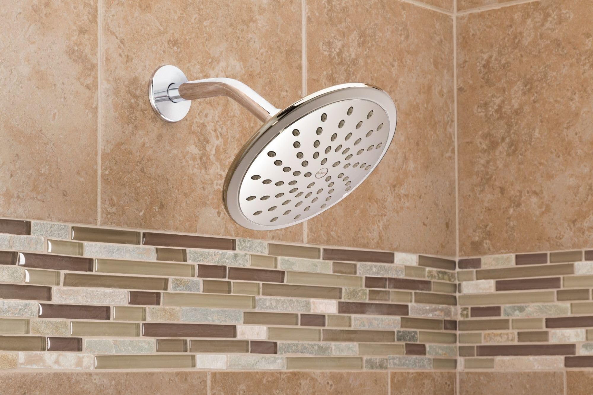 Chrome round rain shower head with curved arm mounted on tile bathroom wall.
