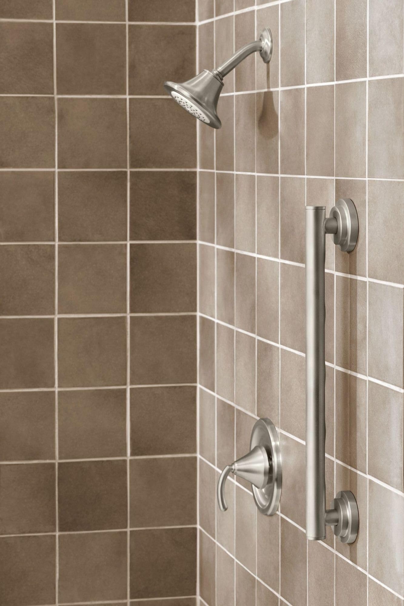 Brushed nickel grab bar mounted vertically on tiled shower wall next to showerhead and controls.