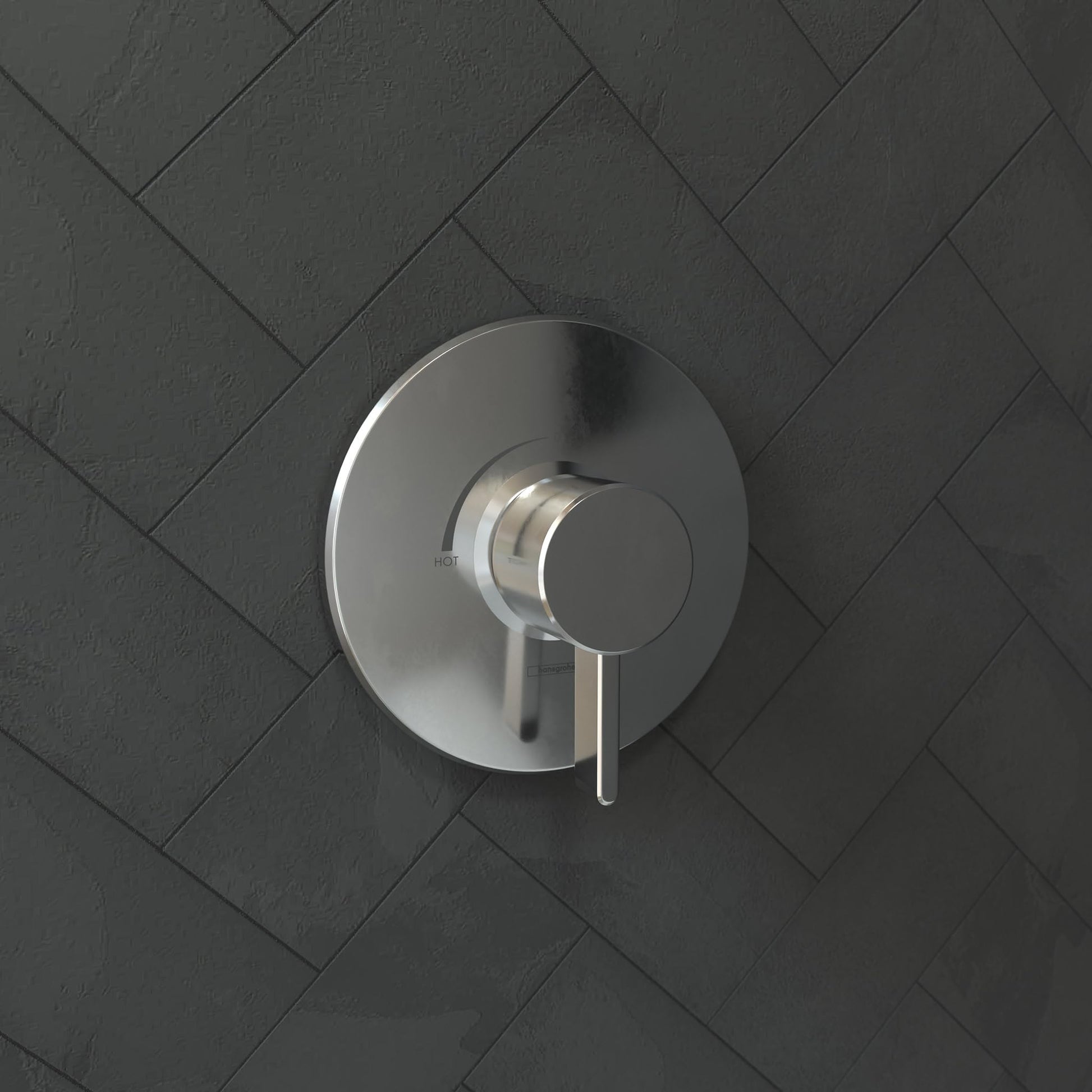 Chrome pressure balance shower valve trim with circular escutcheon plate and lever handle mounted on herringbone tile wall.