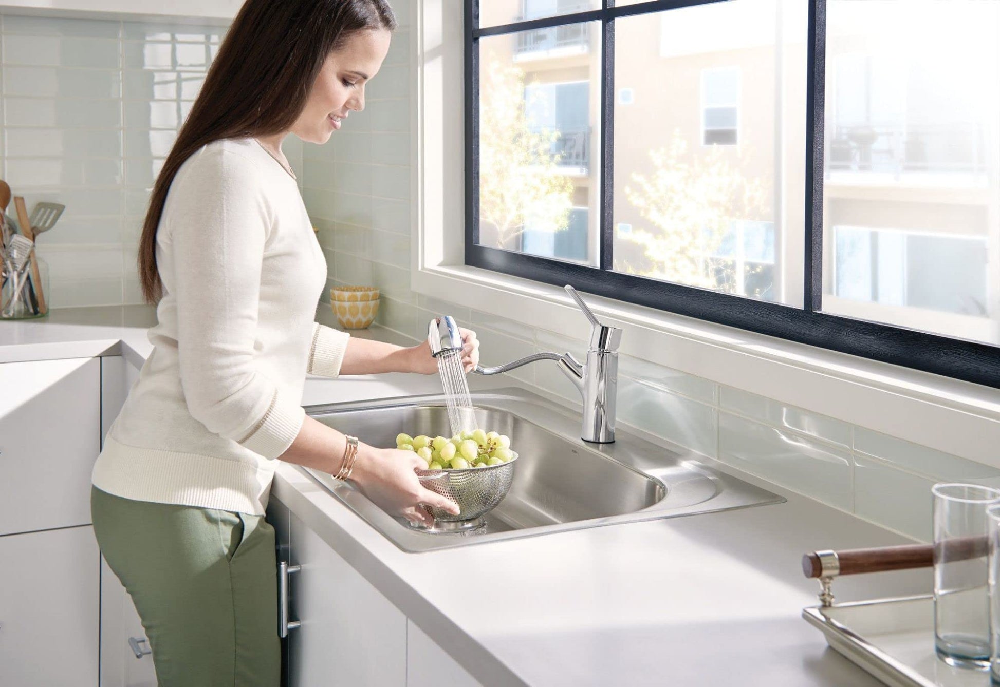 Chrome kitchen faucet with single handle and pull-out sprayer head over white sink.