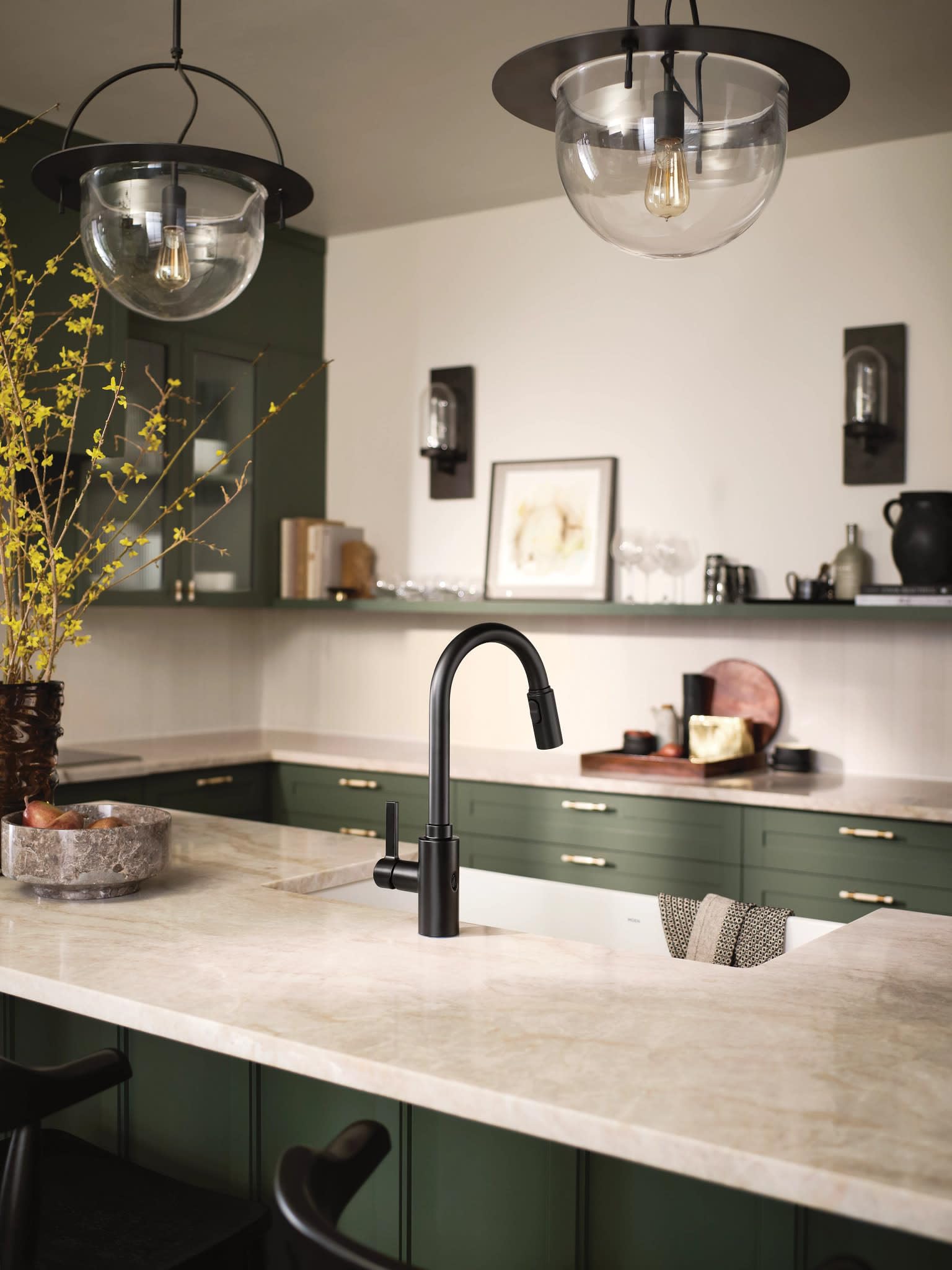 Matte black high-arc kitchen faucet with pull-down sprayer mounted on marble countertop in green cabinetry.