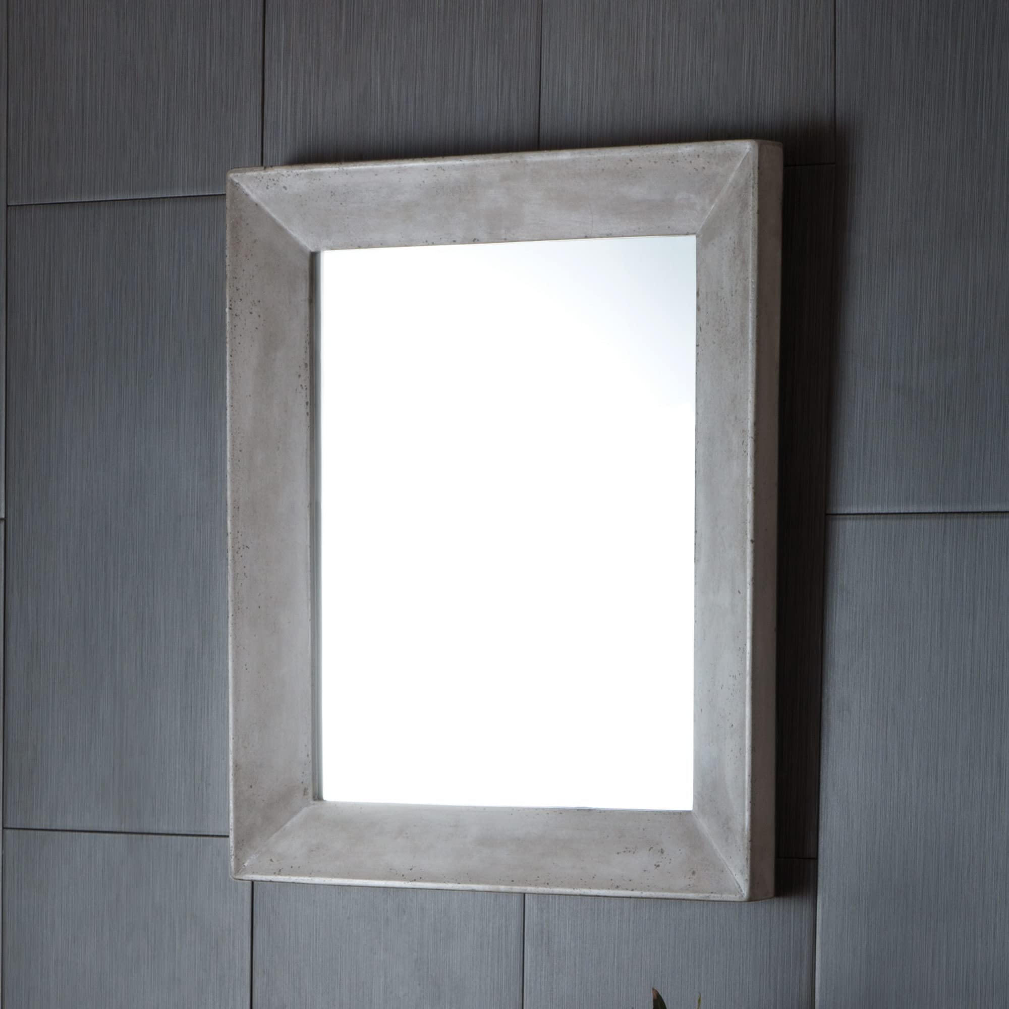 Rectangular wall mirror with concrete frame in pearl finish mounted on textured gray wall.