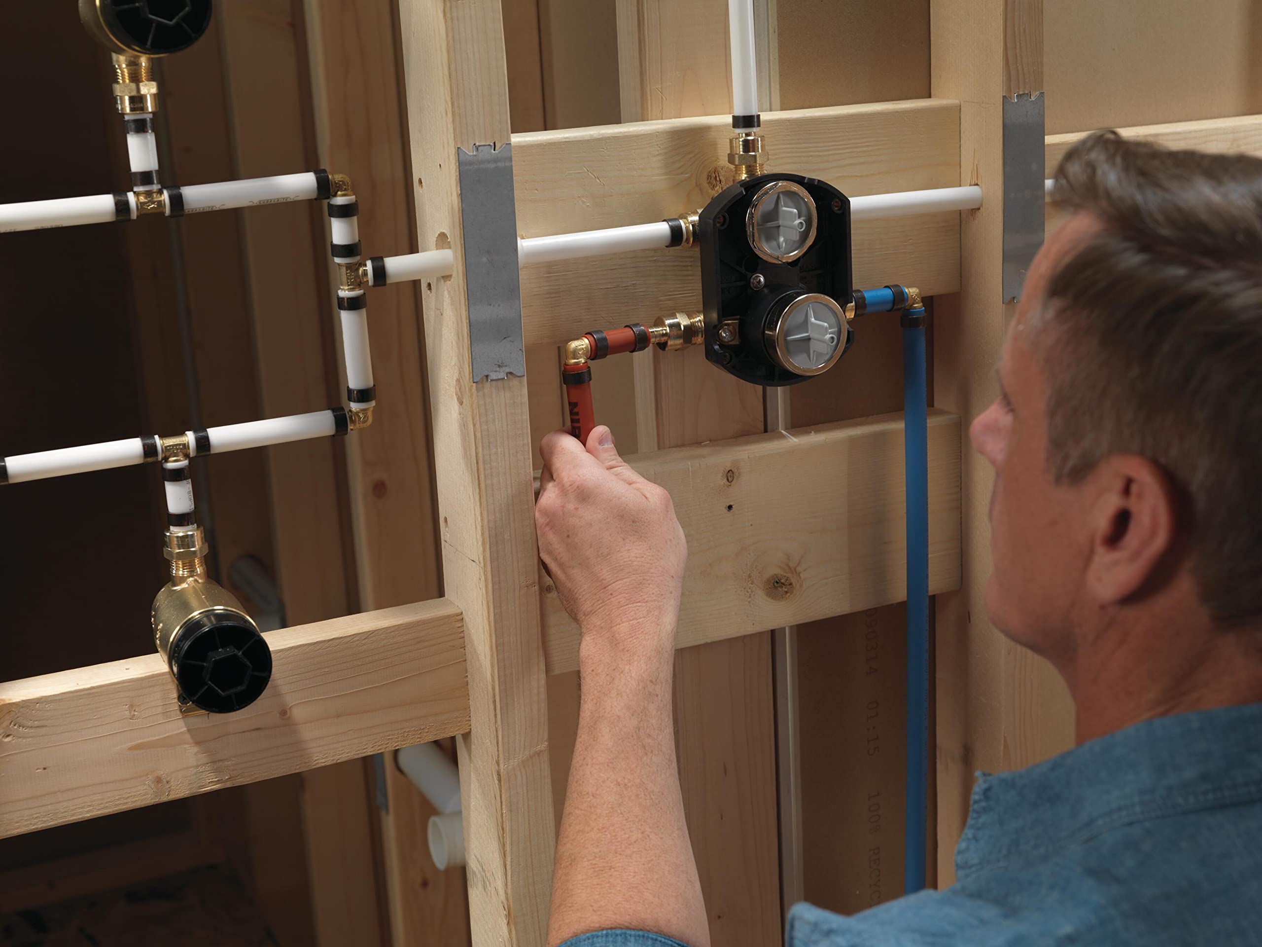 Black integrated shower diverter valve with dual handles mounted on wooden framing during installation.