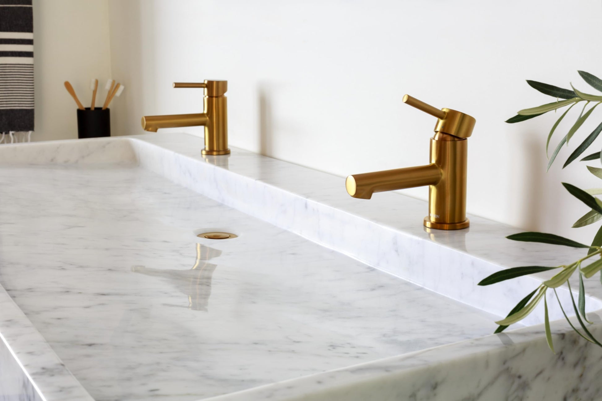 Brushed nickel single-handle low-arc bathroom faucet with angled spout mounted on marble countertop.