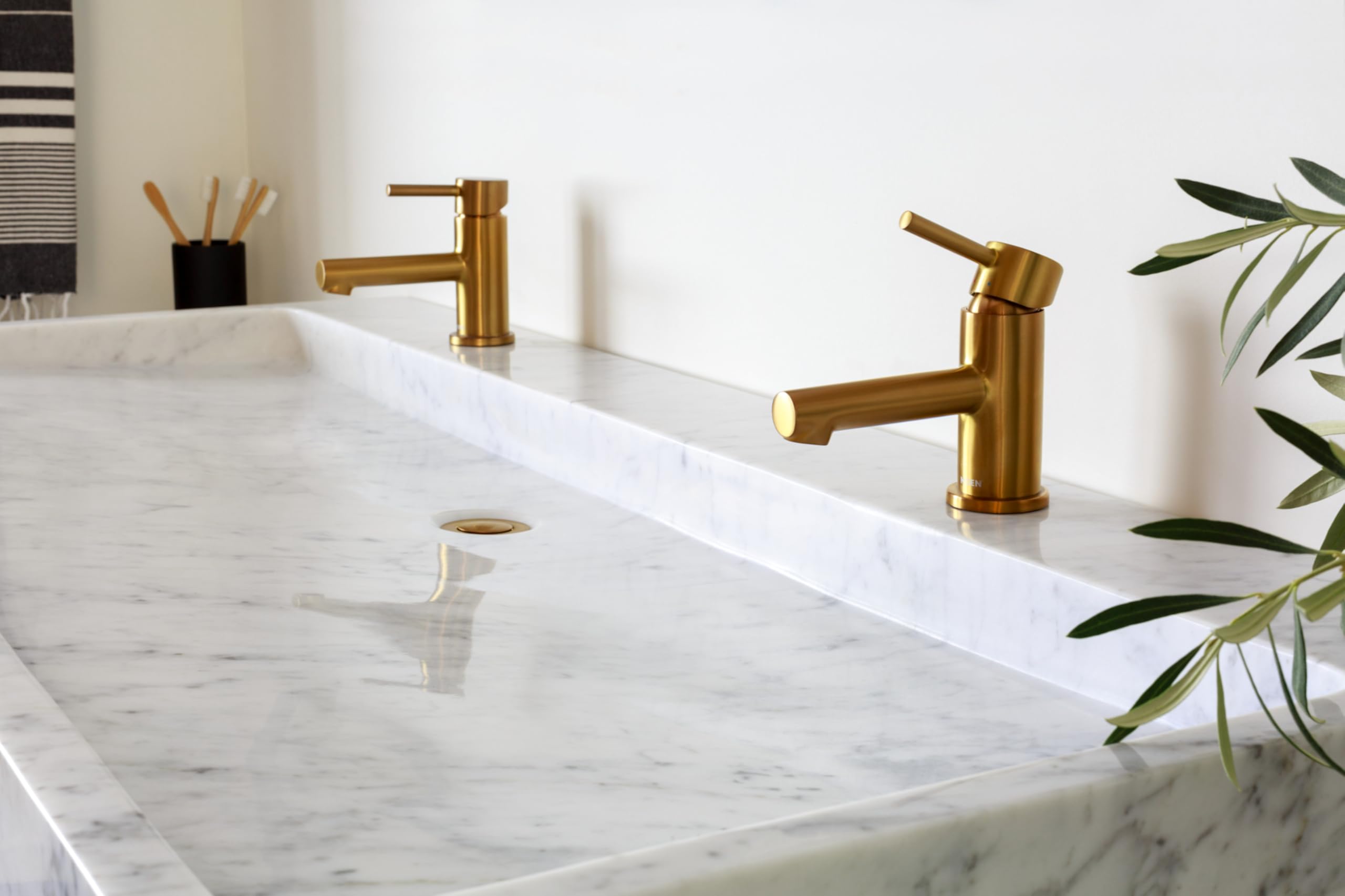 Brushed nickel single-handle low-arc bathroom faucet with angled spout mounted on marble countertop.