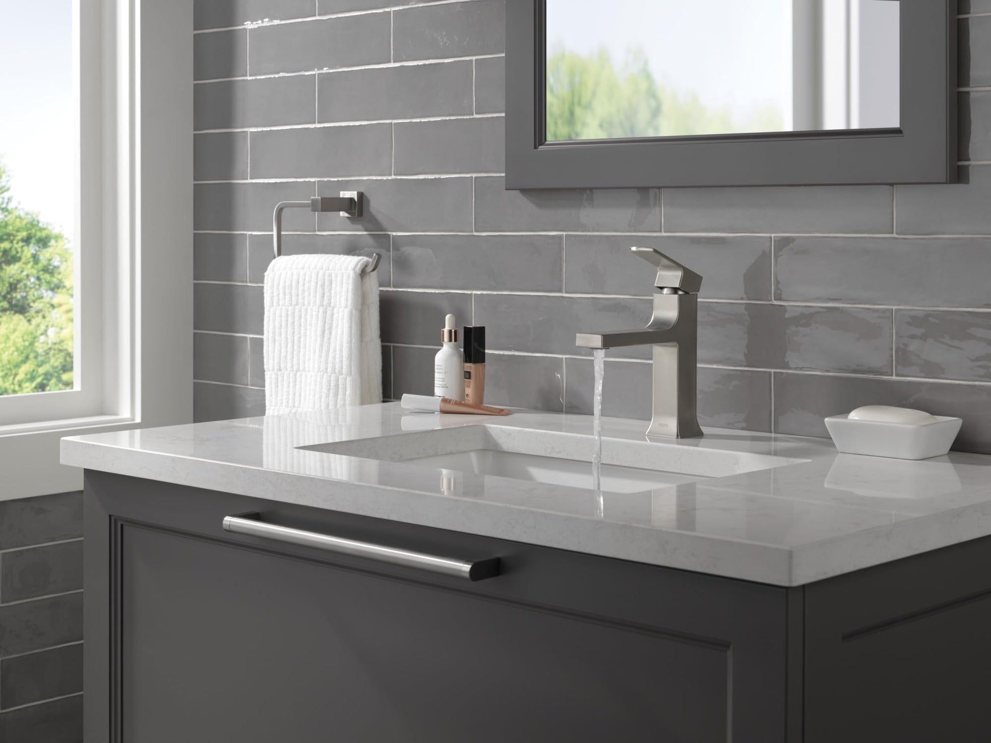 Stainless steel single-handle bathroom faucet with angular spout mounted on white countertop sink.