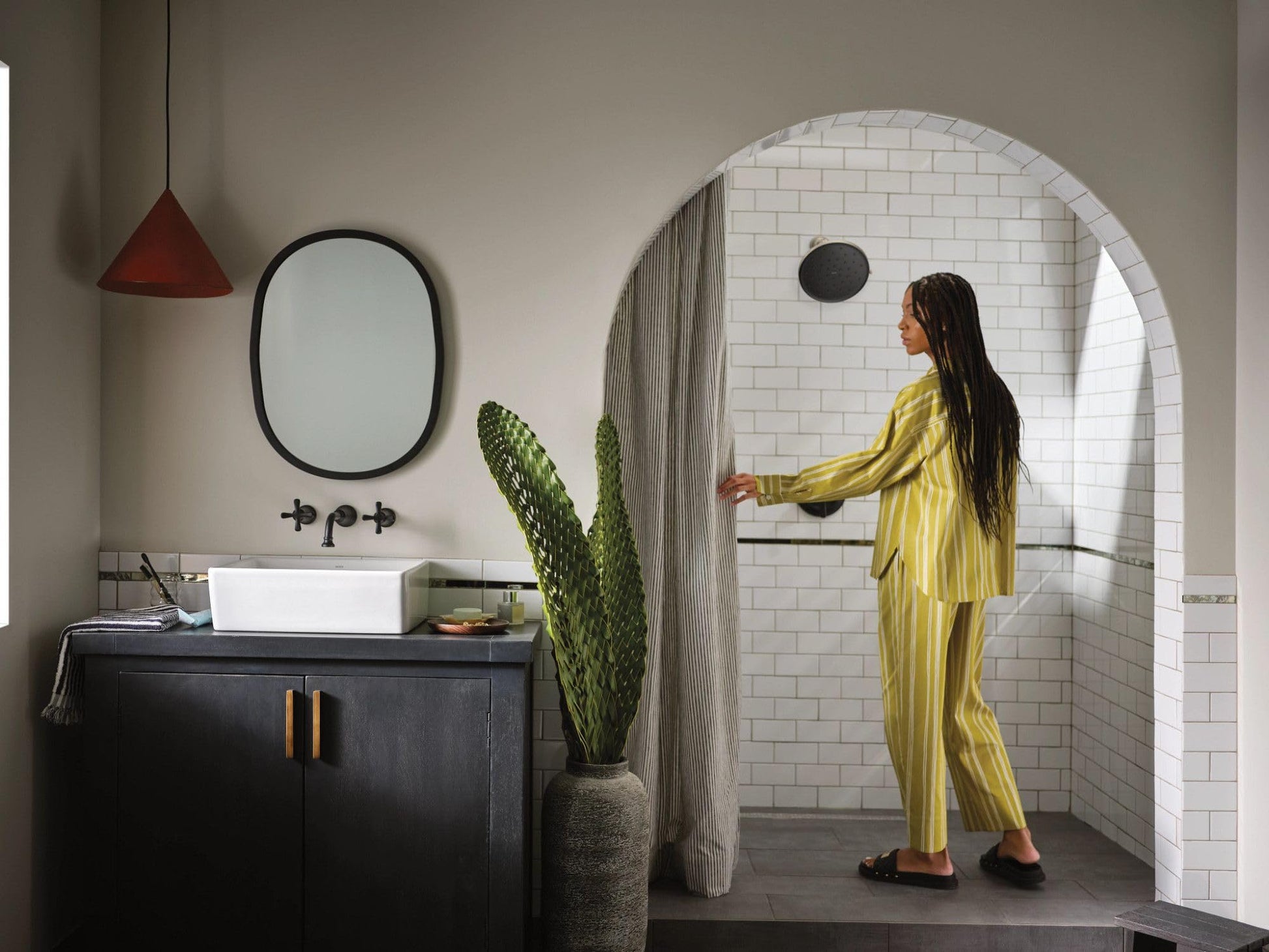 Matte black single-handle shower trim kit mounted on white subway tile wall in bathroom enclosure.