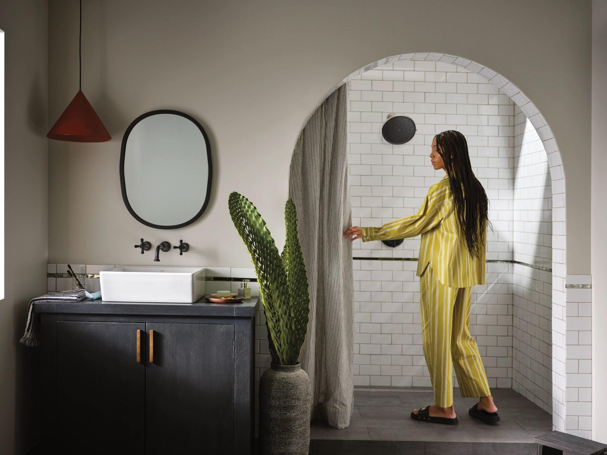 Matte black single-handle shower trim kit mounted on white subway tile wall in bathroom enclosure.